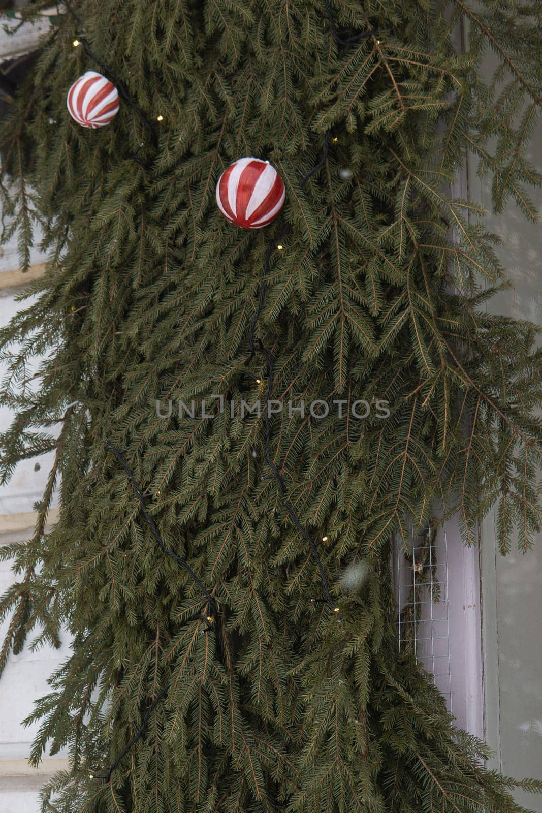 Christmas trees decorated with red balloons in front of the cafe entrance. Street New Year decorations.