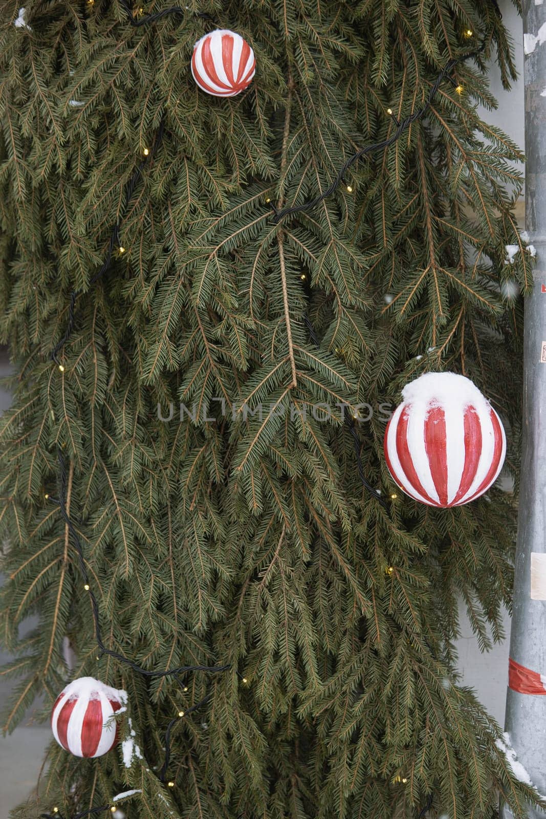 Christmas trees decorated with red balloons in front of the cafe entrance. Street New Year decorations.