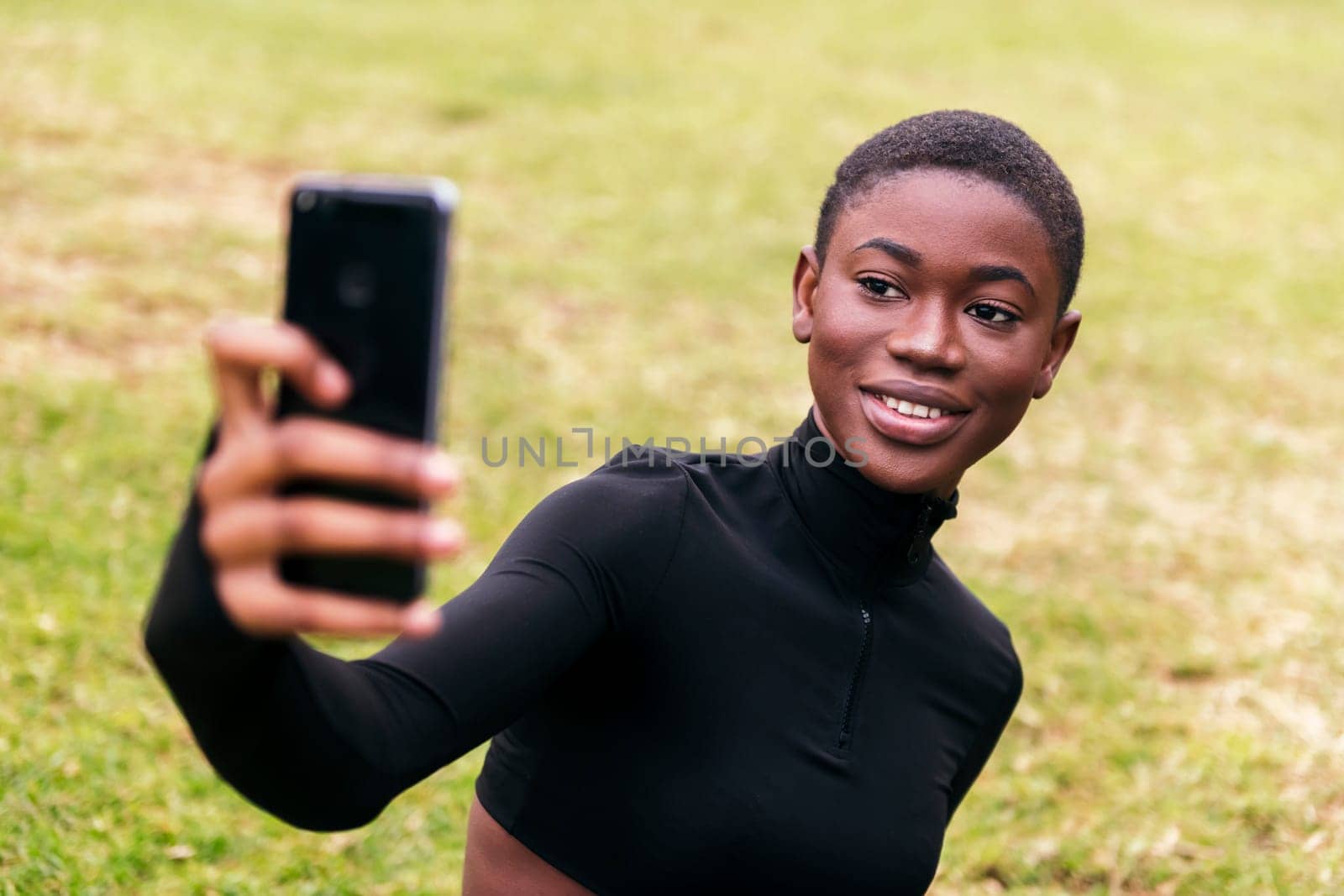 young ethnic female in casual apparel smiling happy taking self portrait on mobile phone in a park