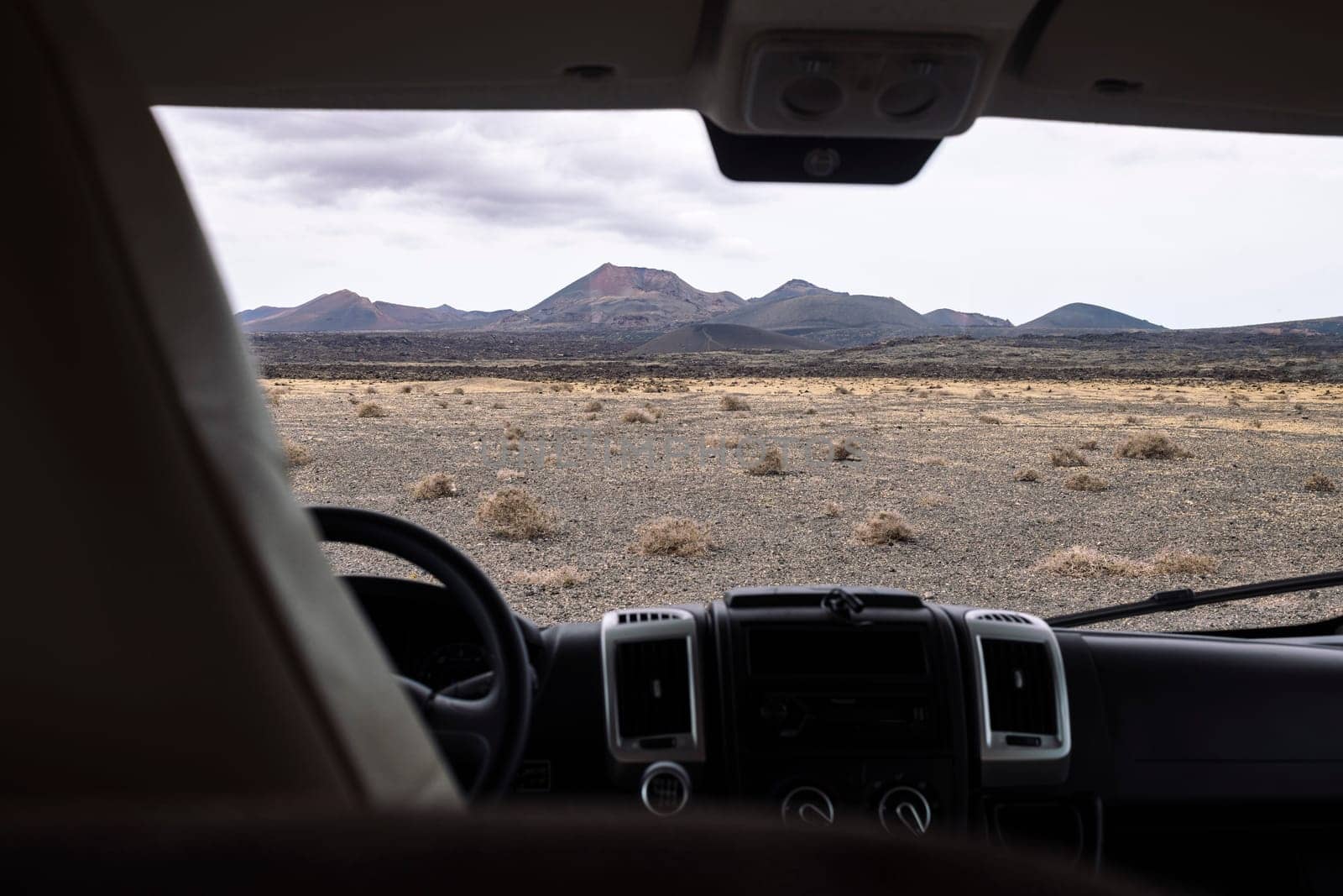 from inside vehicle view of volcano Cuervo and mount under cloudy sky in Tinajo, Lanzarote at Canary Islands Spain, concept of travel and adventure in nature