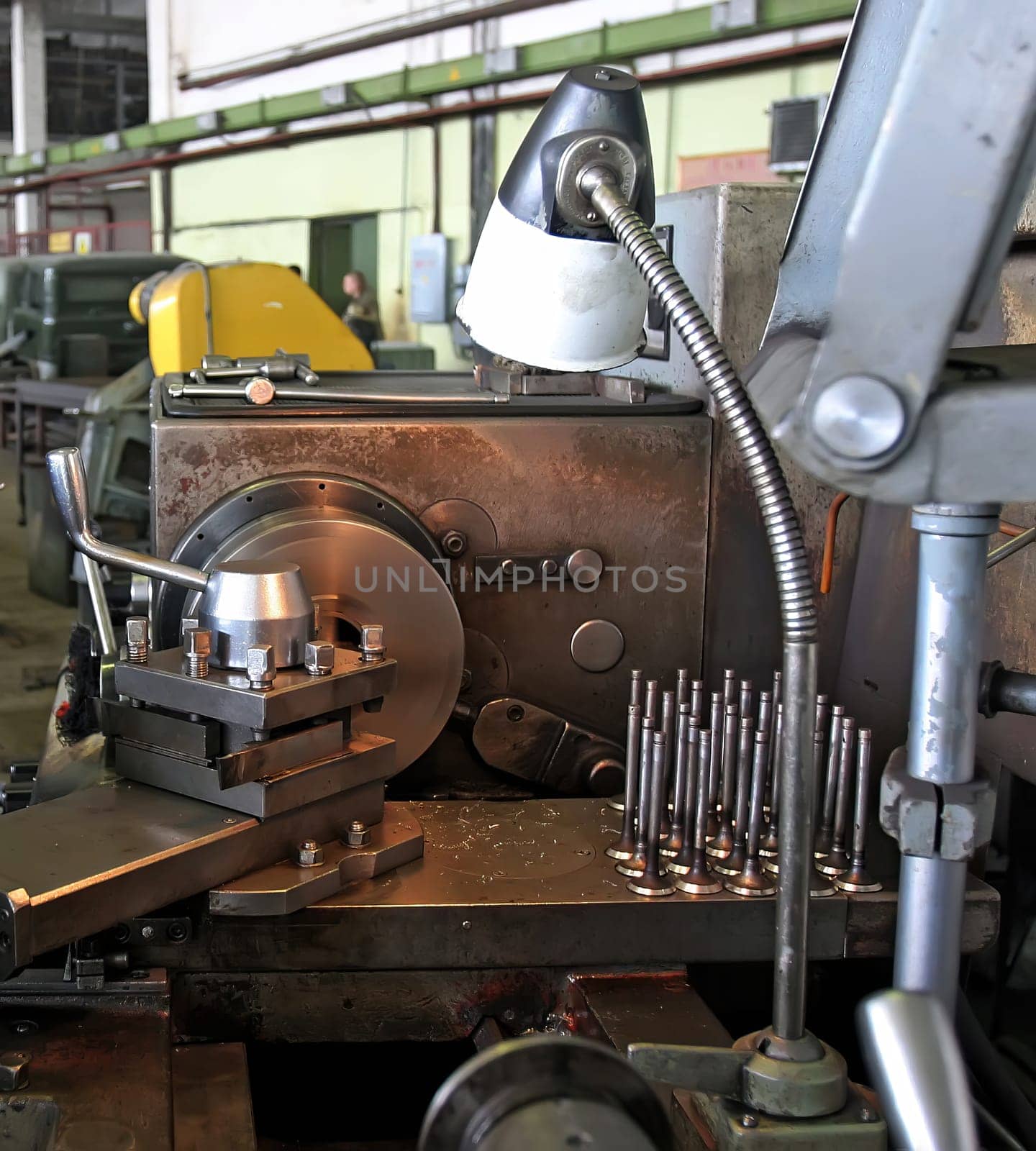 A skilled technician expertly operates a lathe in a lively workshop, surrounded by various metal parts and tools, showcasing the art of precision machining.