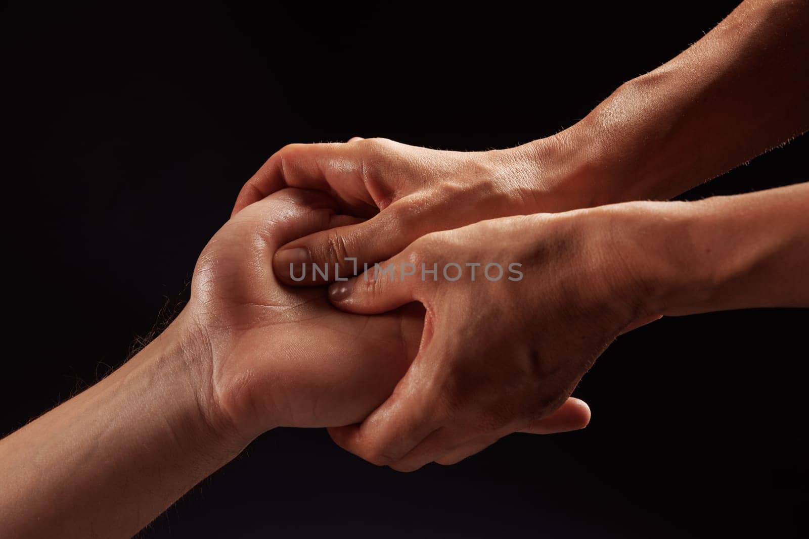 girl masseur doing hand massage to man on dark background close-up, beautiful relaxation massage, recovery