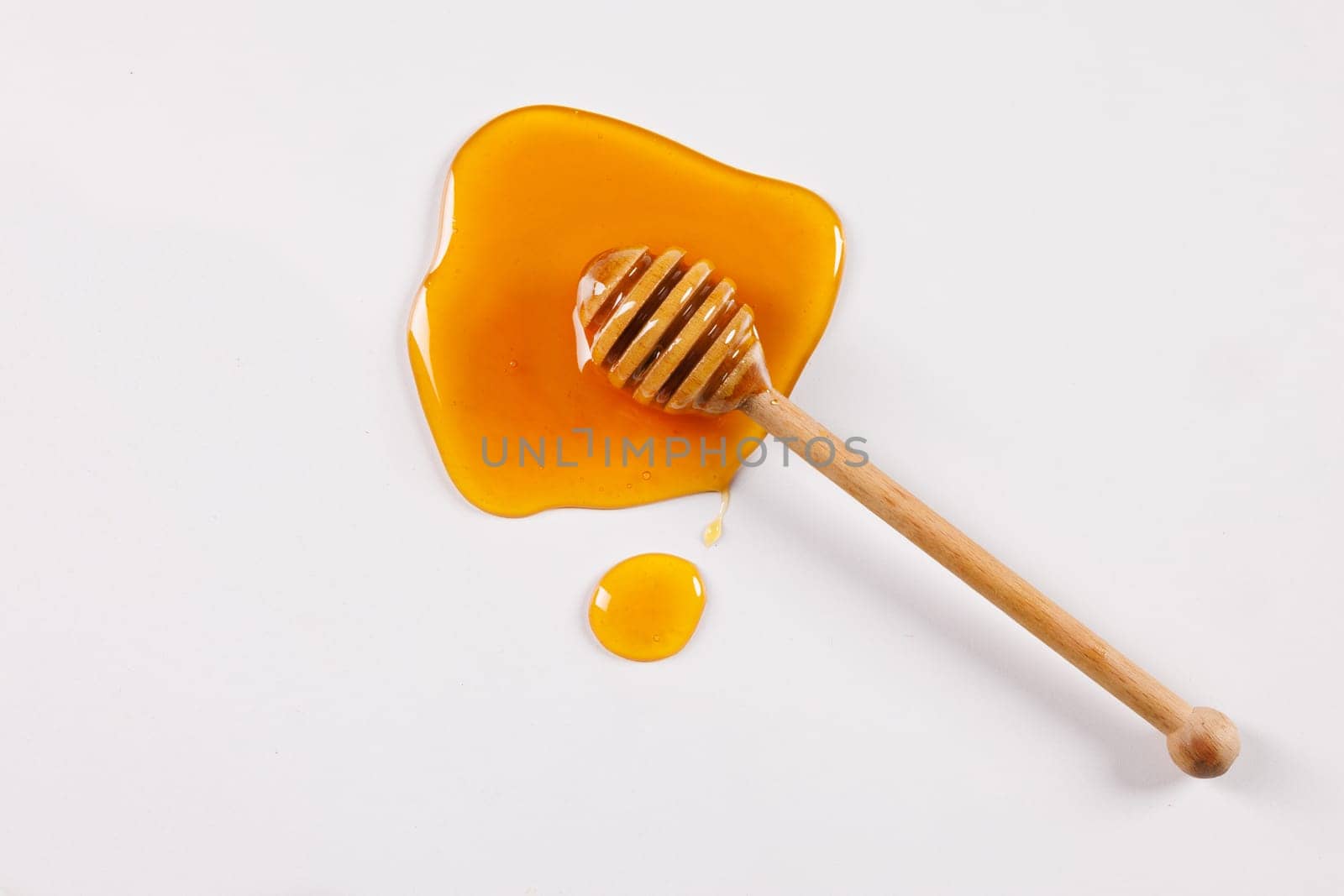 honey spoon with spilled honey on white background, top view, honey benefits concept