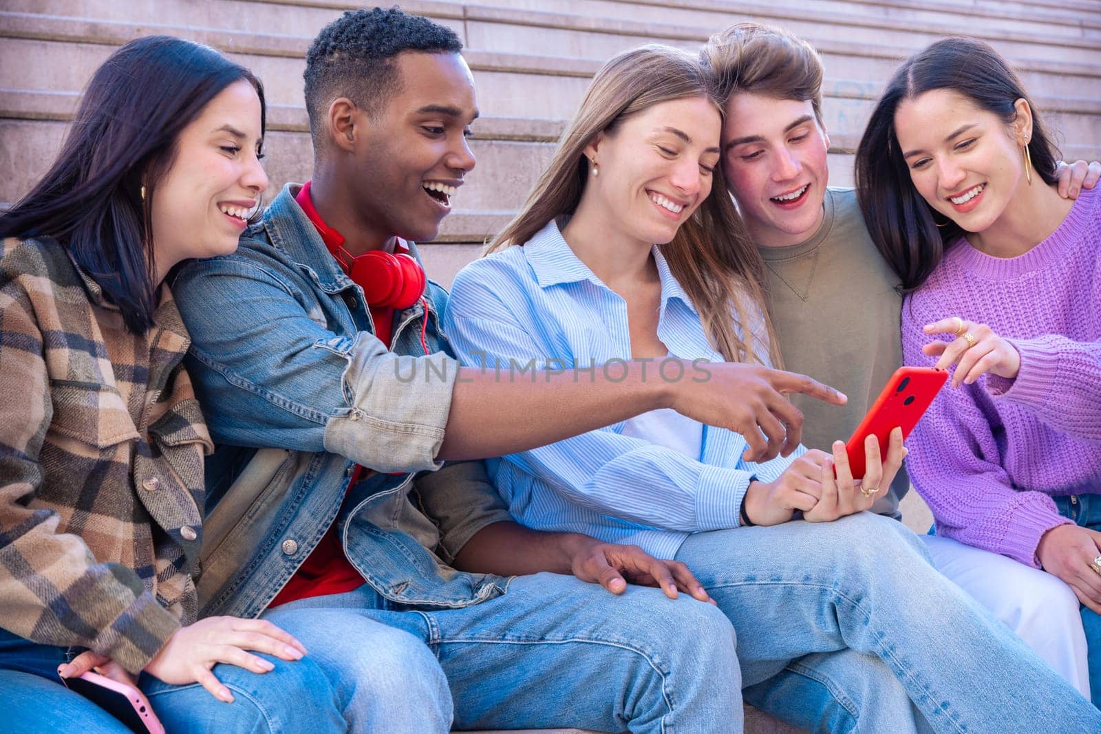 Group of friends using looking at their smartphones Multiracial teenagers browsing the internet with mobile phone on campus