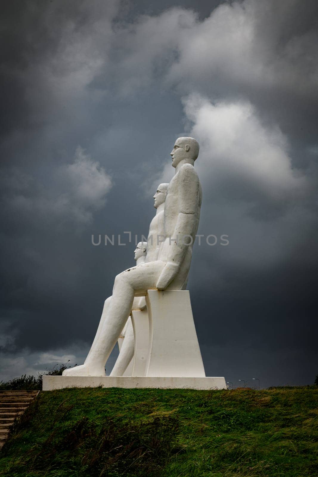 White Men statues, Esbjerg, Denmark. Four white men sitting looking at the sea near Esbjerg, Denmark. They are each 9 meters tall and made of white concrete.