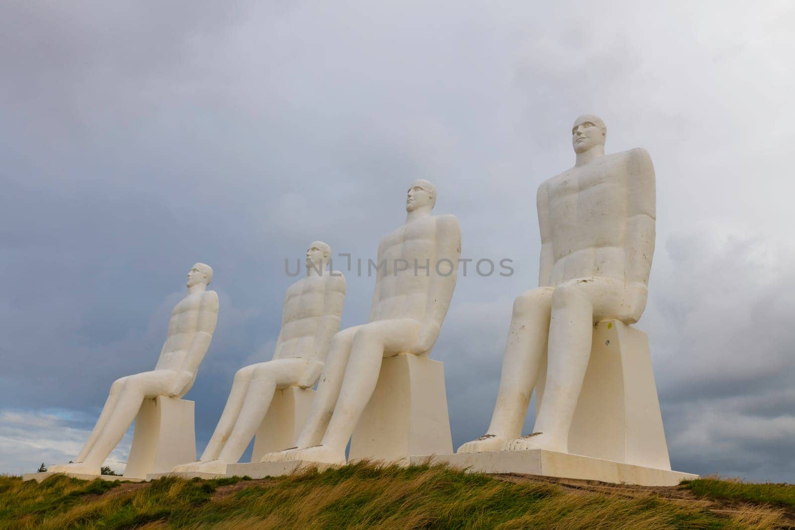 White Men statues, Esbjerg, Denmark. Four white men sitting looking at the sea near Esbjerg, Denmark. They are each 9 meters tall and made of white concrete.