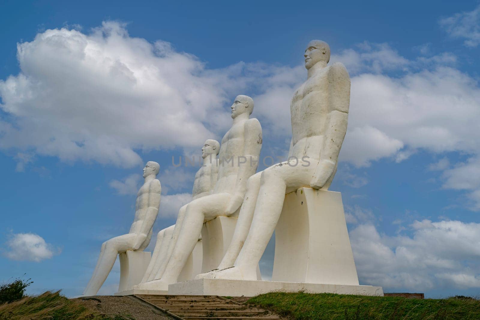 White Men statues, Esbjerg, Denmark. Four white men sitting looking at the sea near Esbjerg, Denmark. They are each 9 meters tall and made of white concrete.