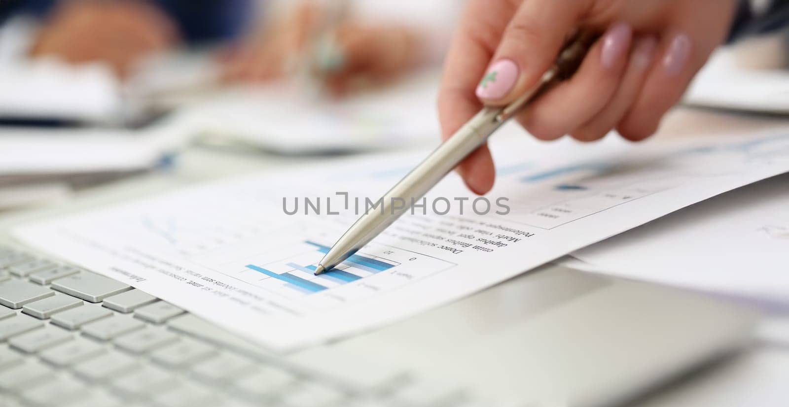 Close-up of man going through financial report paper with silver pen. Qualified worker in office, doc over keyboard. Business, statistics, success concept