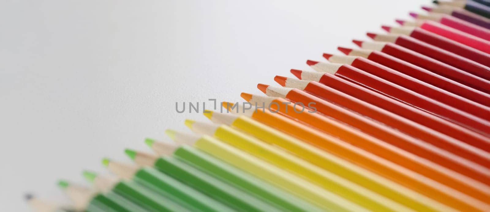 Close-up of pencils set perfectly placed in line on white surface for childs art. Crayon ready for drawing and create masterpiece. Creativity, art concept