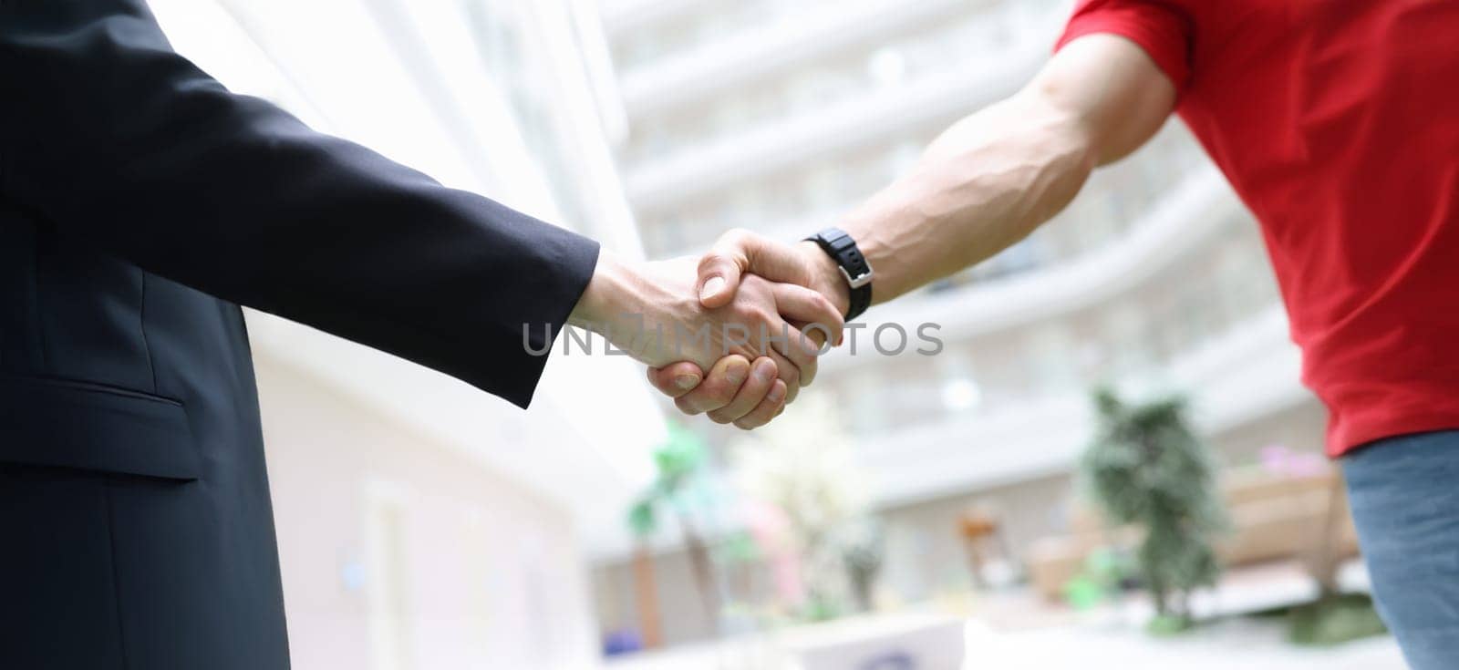 Handshake businessman and men in a red T-shirt, close-up. Freelancer, cooperation agreement. Promotion