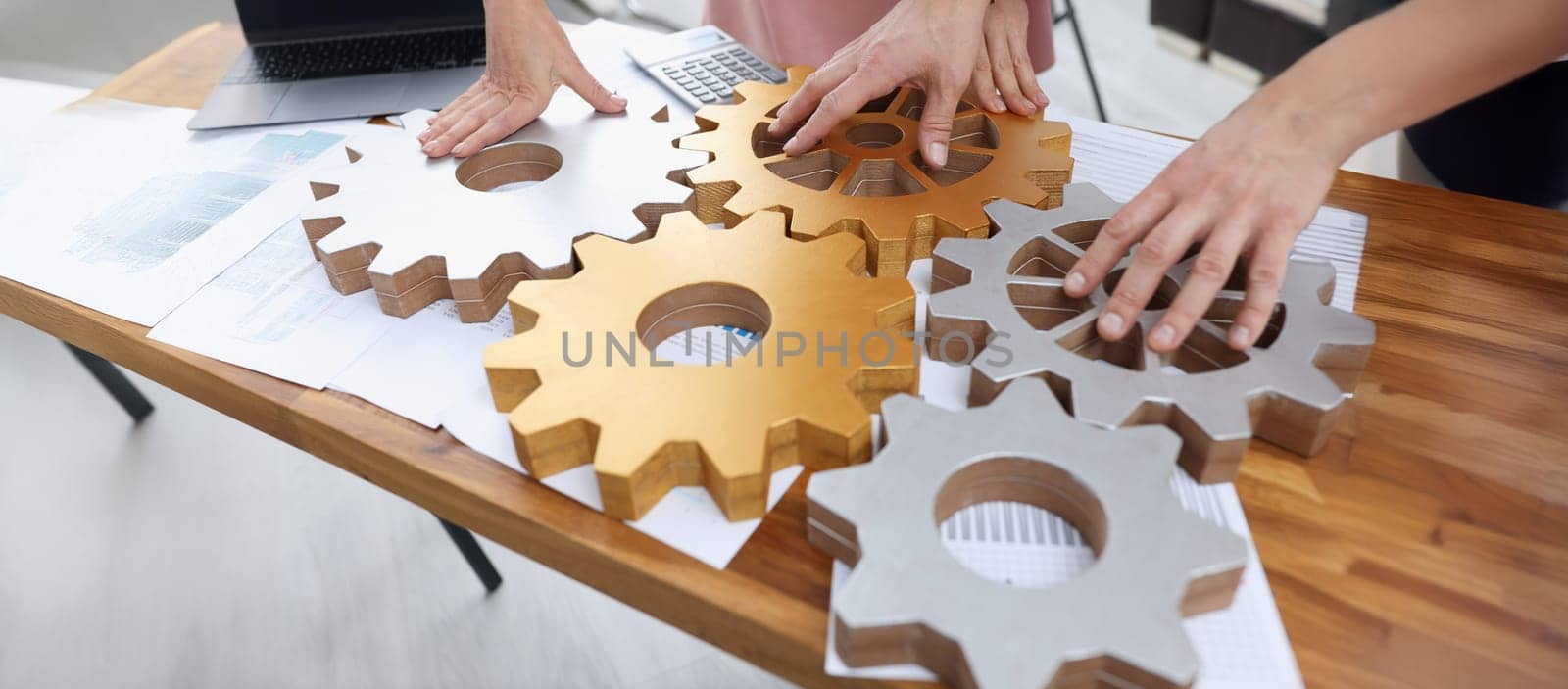 Businessmen are stacking gold and silver gears, close-up. Business interaction, collaboration and partnership concept
