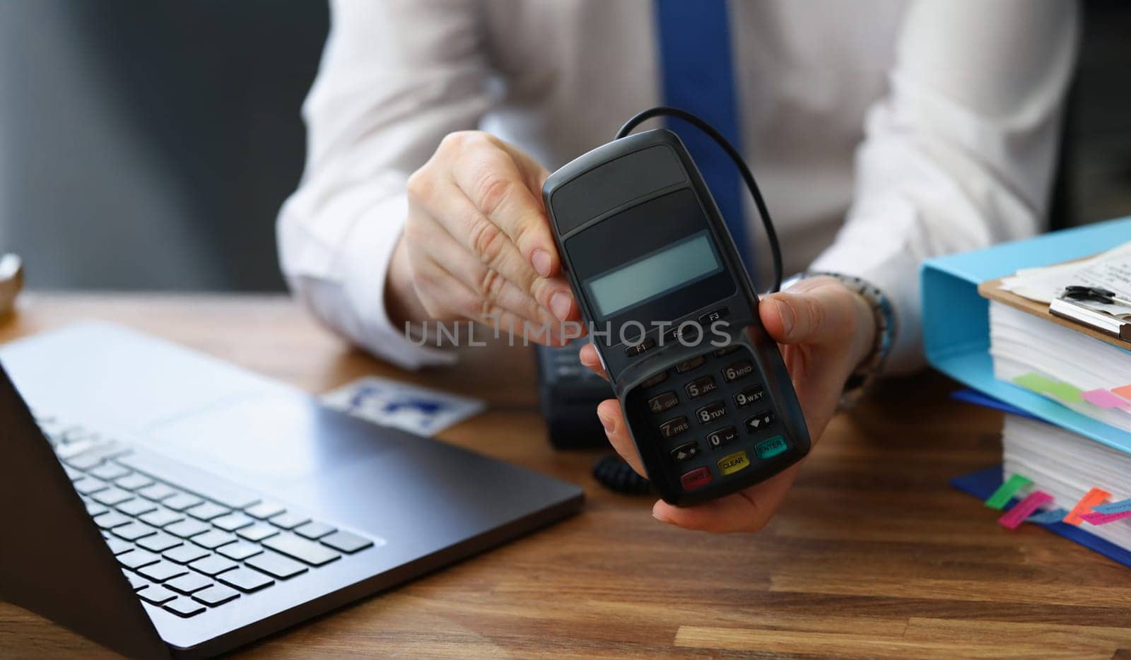 Close-up of man holding modern credit card reader machine for cashless payment. Empty screen for total cost and numbers on pad. Modern technology concept