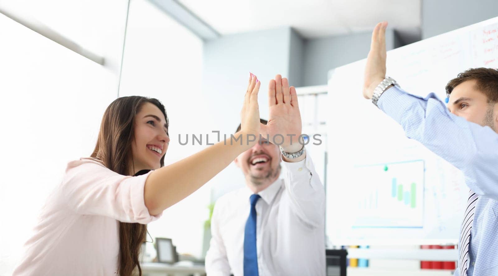 Portrait of team clapping hands together giving high five to celebrate finished business project. Successful teamwork in company office. Success concept