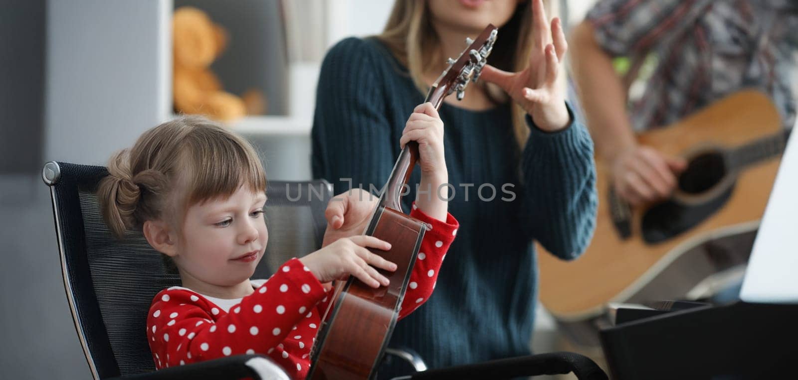 Portrait of mother take musical instrument from daughter hands to show how to play. Parent and daughter form home band. Music, creativity, talent concept
