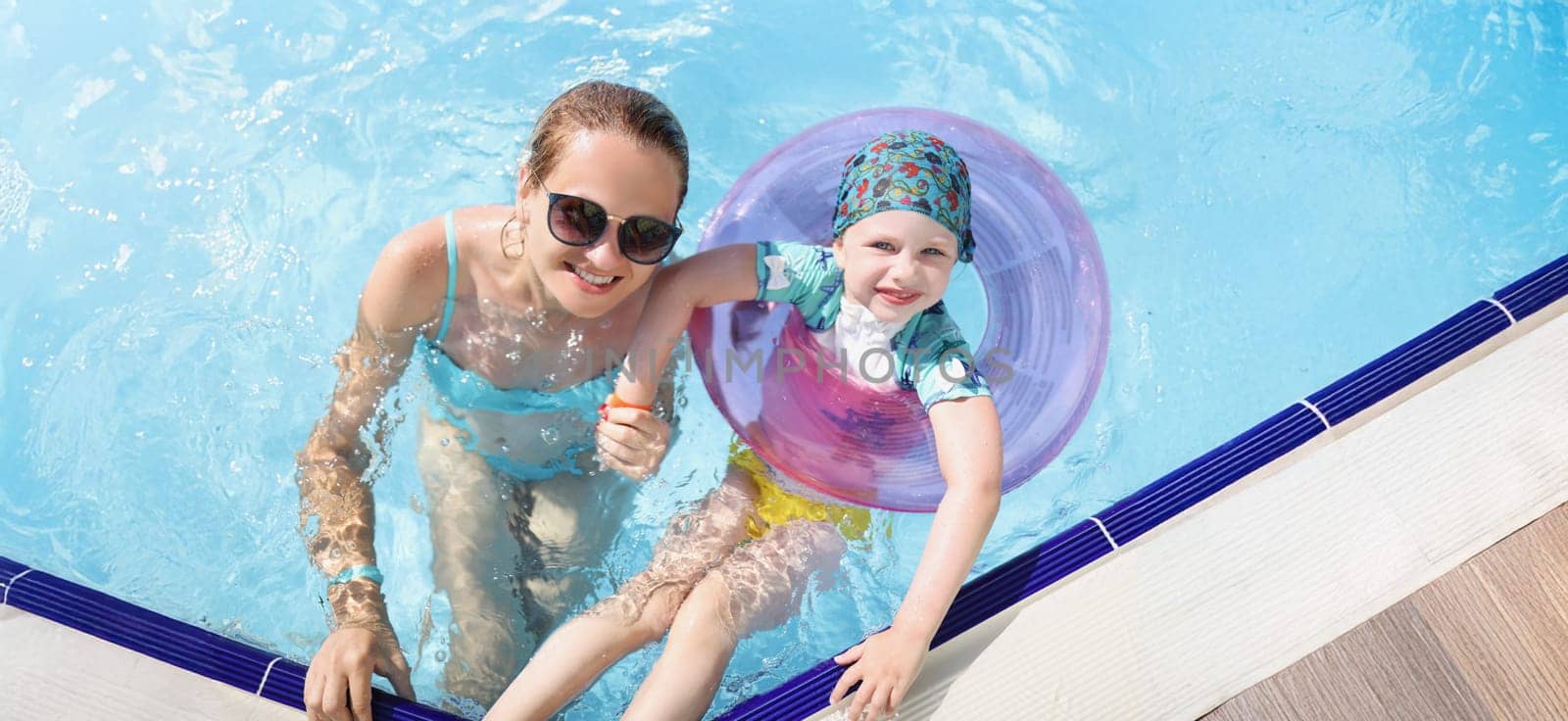 Top view of mother and daughter swimming in pool enjoy summer holiday. Smiling and happy parent and child on resort. Summer, childhood, parenthood concept