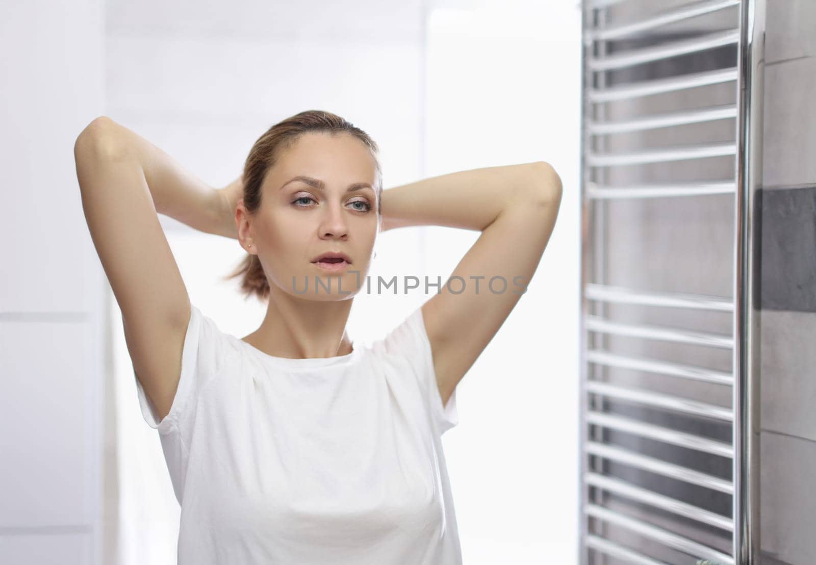 Portrait of young woman looking in mirror at herself in bathroom, pretending shes beautiful, morning routine. Good morning, wellness, beauty ritual concept