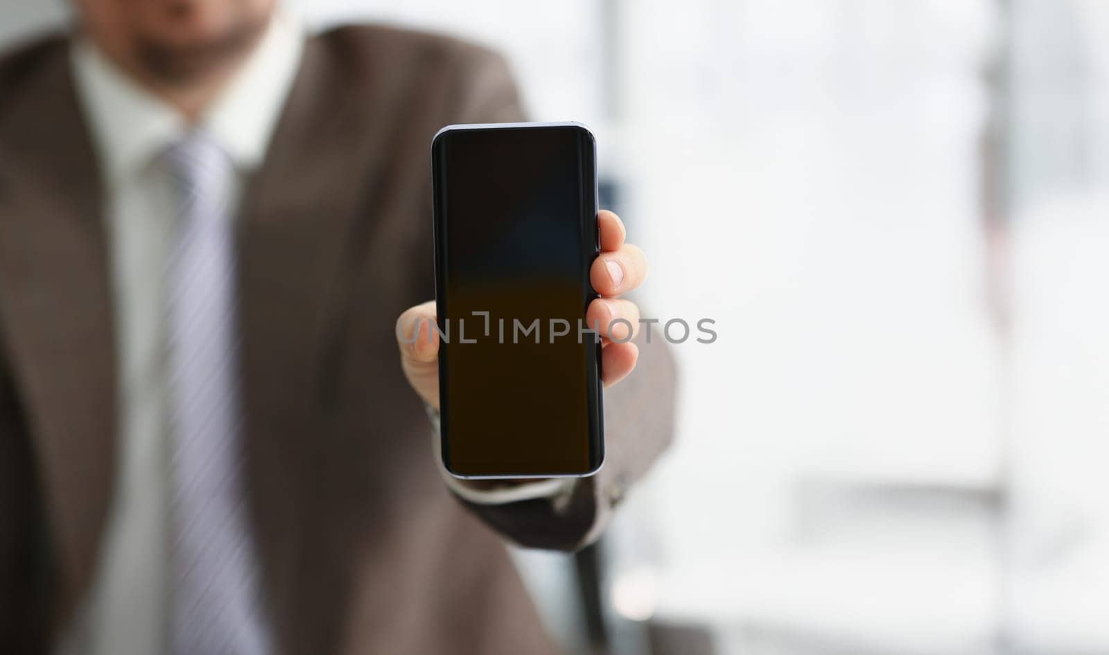 Close-up of male arm in suit show in camera mobile phone display with black screen. Broken or locked smartphone, not working. Mockup, copy space concept
