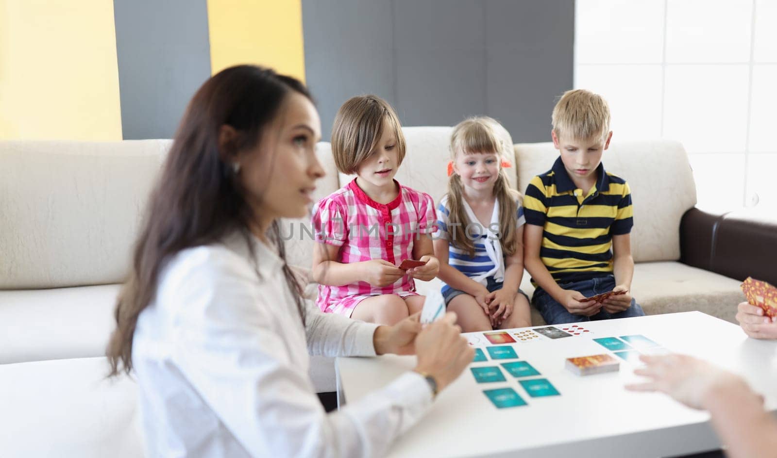 Portrait of group of kids spending time in kindergarten with female teacher. Woman entertain children with games and active pastime. Childhood, fun concept