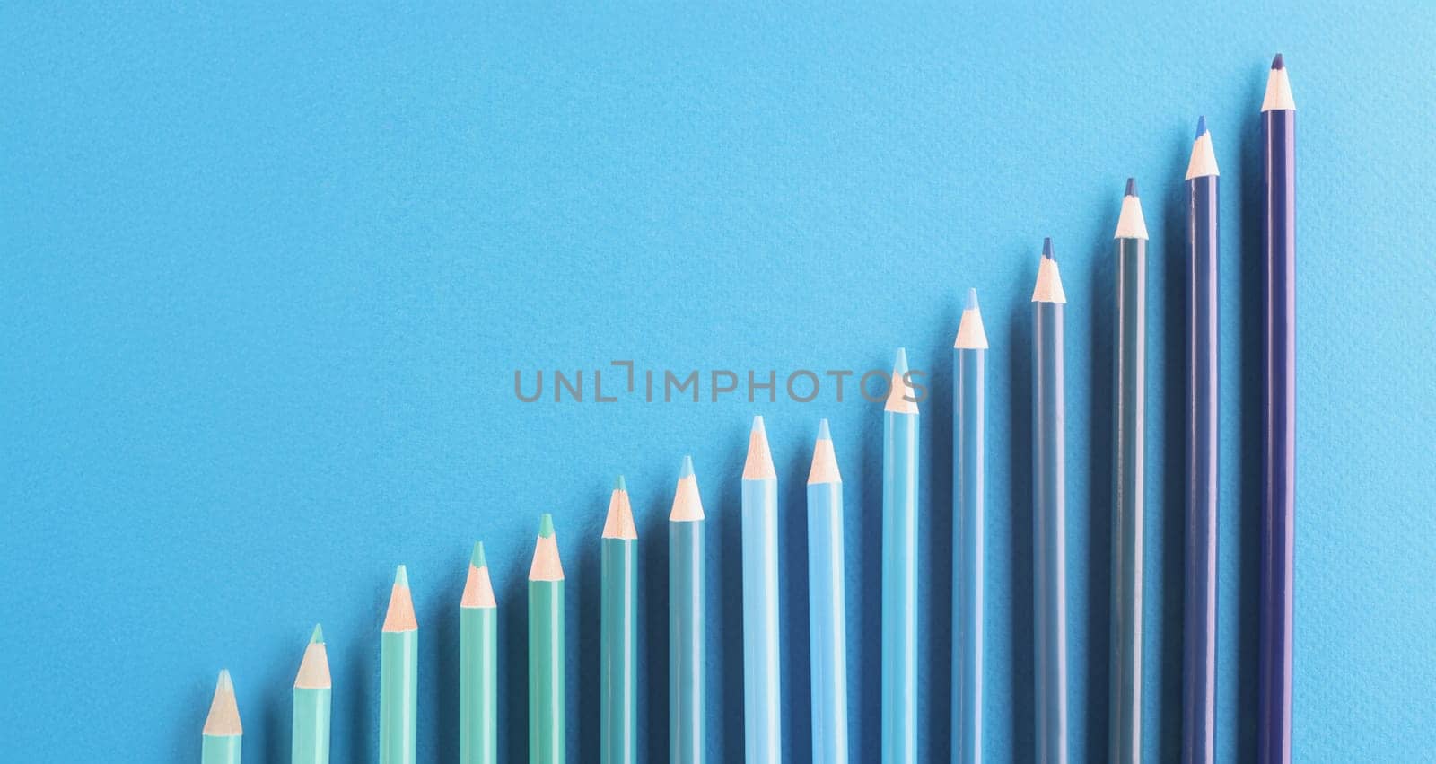 Top view of blue colored pencil set arranged in increasing way on surface and not exactly in row. Tool for draw your dreams, ideas and vision. Art concept