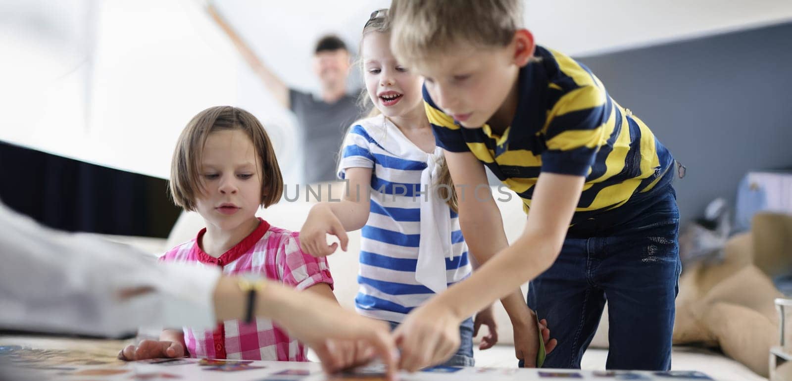 Portrait of kids friends busy with playing card game on table at home. Funny pastime for children and development. Childhood, holiday, fun weekend concept