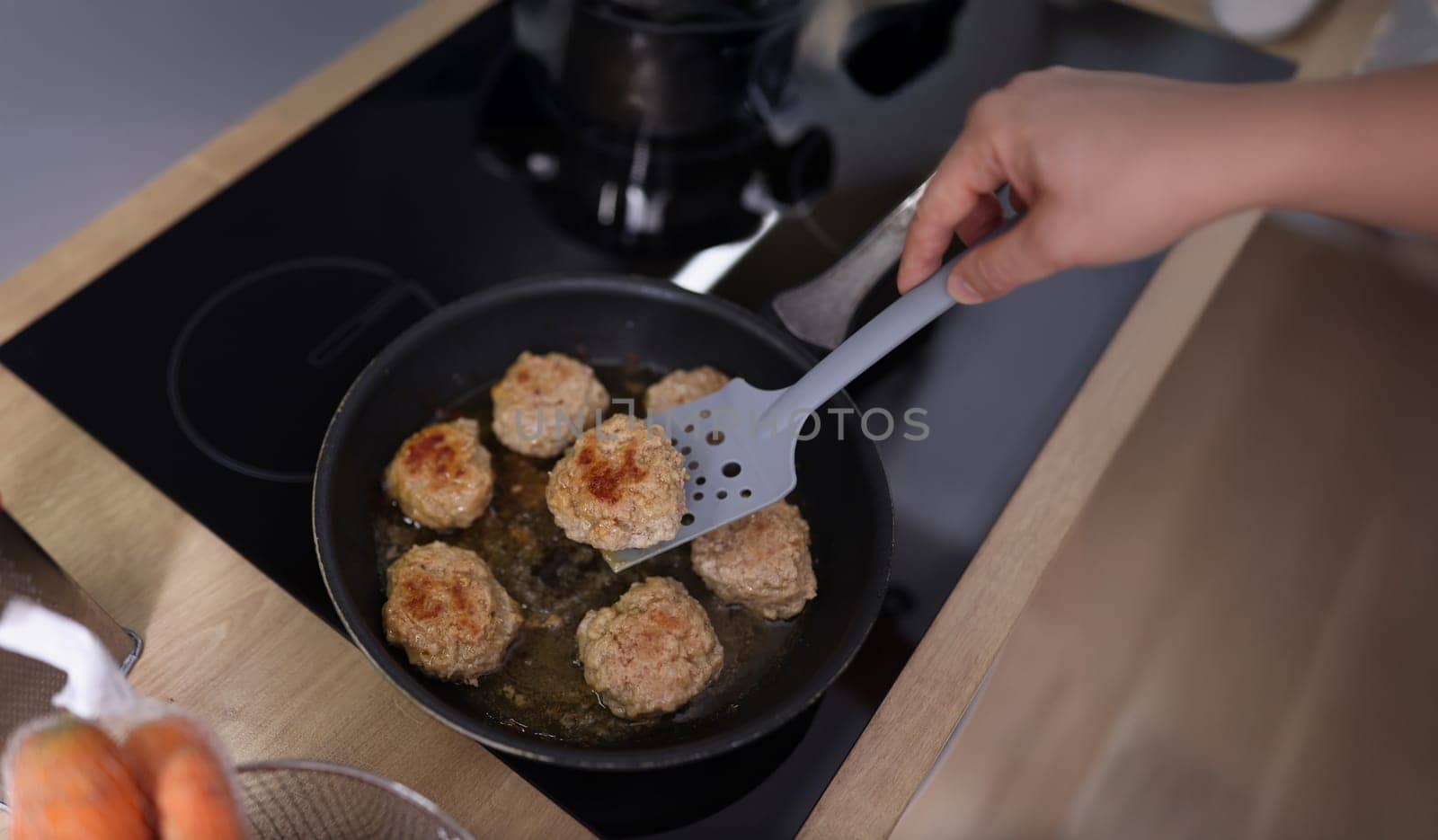 Top view of meat balls beginning to fry in oil in frying pan on kitchen stove. Housewife cooking fresh meal using tool. Chef, food, eating, dish concept