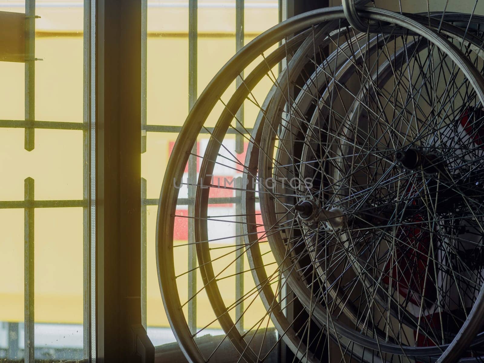 Vintage bicycle wheels in a cozy repair shop, leaning against a sunlit window, waiting for expert attention