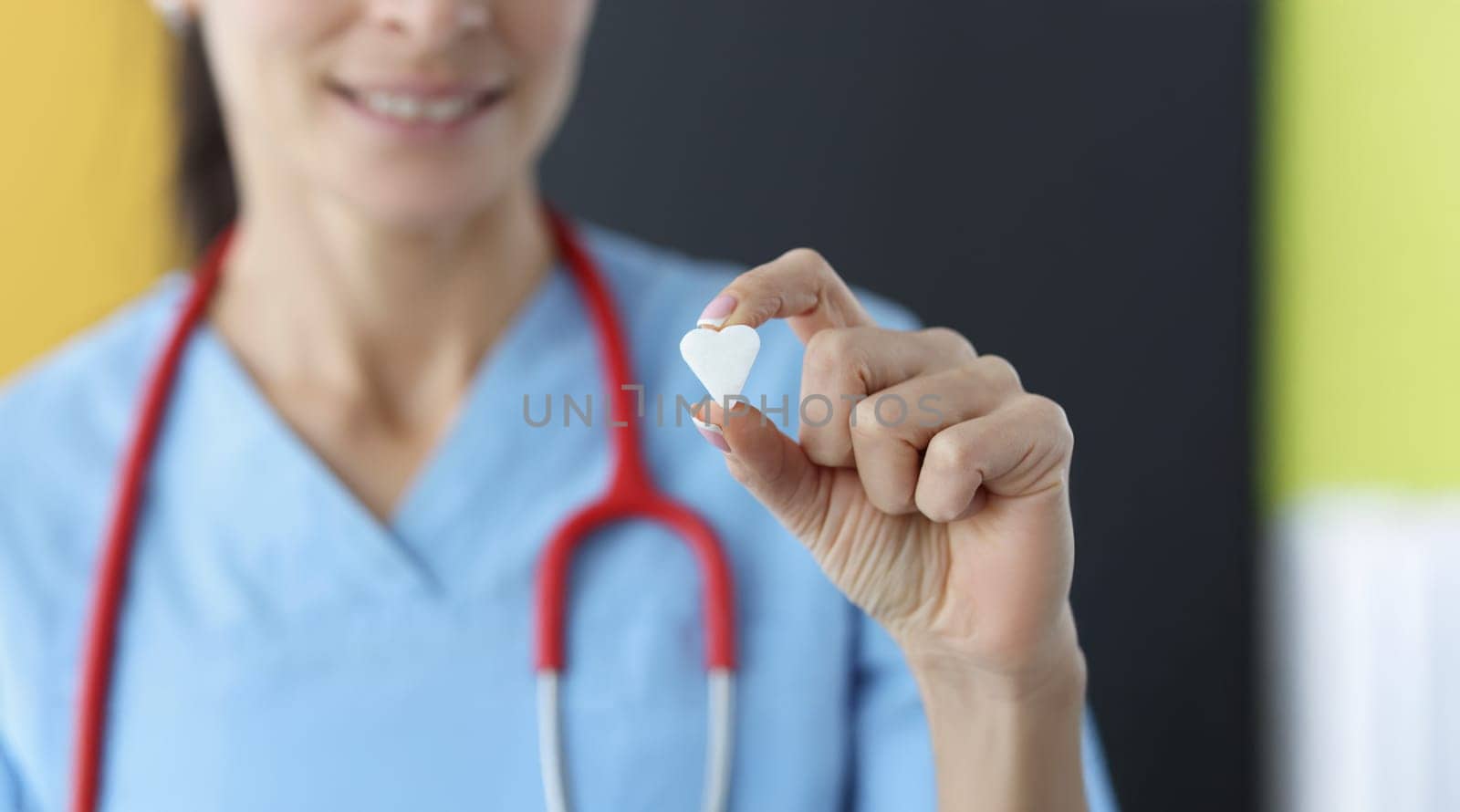 Close-up of female medical worker show small white heart on camera. Save life through donation or charity. Medicine, cardiology, healthcare, help concept