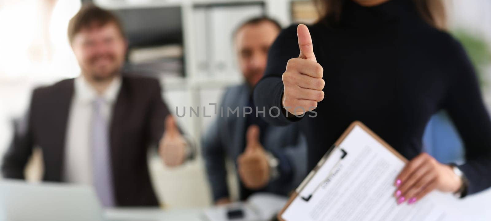 Close-up of group of young businesspeople happy to make good deal show thumbs up. Business partners made successful agreement in office. Business concept