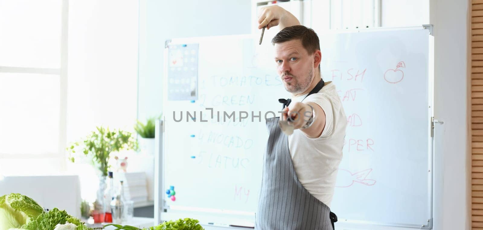 Portrait of attractive male chef standing in apron and pretend hes fighter with cooking knife. Blogger chef discover healthy eating habits. Food concept