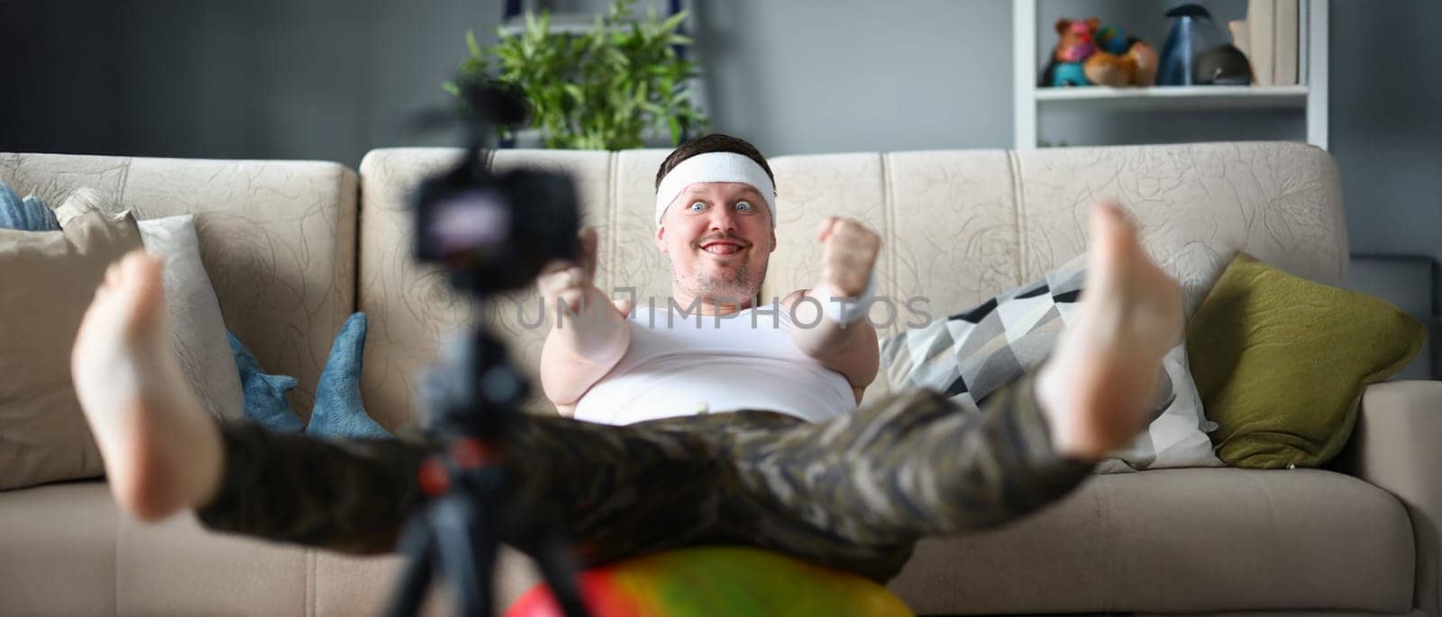 Portrait of man in sportswear perform exercise on ball with funny facial expression. Active person start channel on social media. Internet, sport concept