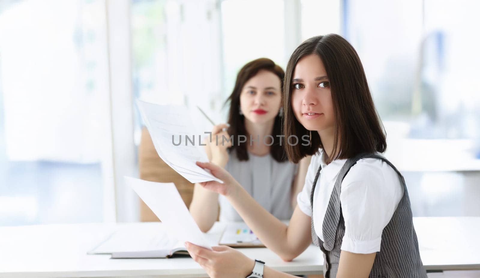 Portrait of business women working on monthly report surrounded with bunch of papers. Colleagues workers in company office. Business, corporate concept