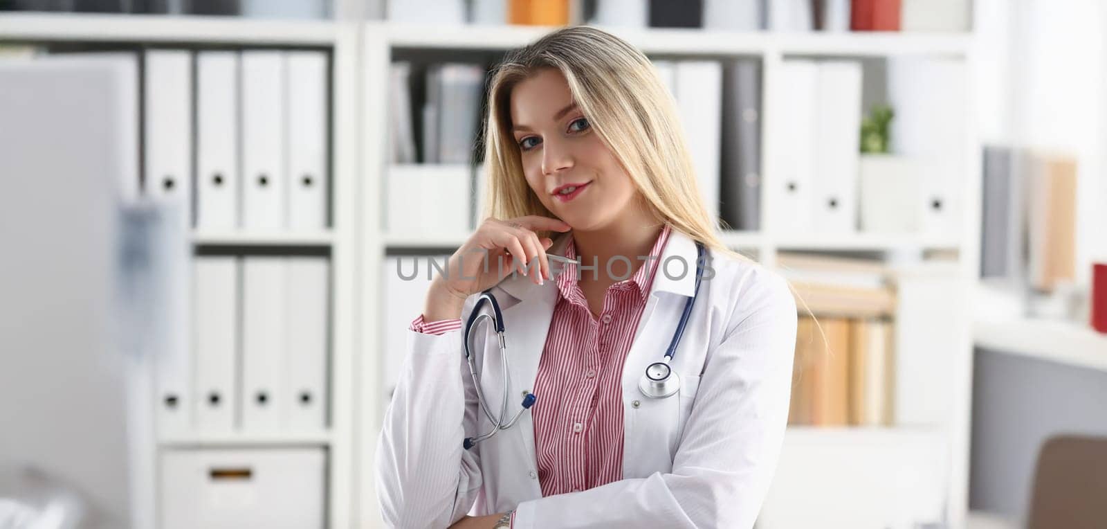 Portrait of beautiful smiling female doctor sit at workplace in special uniform. Physical and disease prevention, prescribe remedy, health, clinic concept