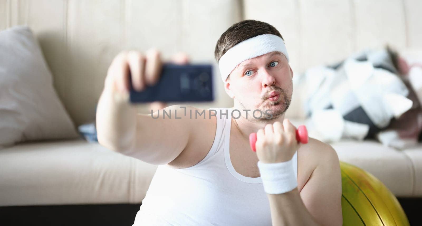 Portrait of sportsman training at home lifting dumbbell and take selfie for social media channel. Middle aged blogger create sport content. Hobby concept