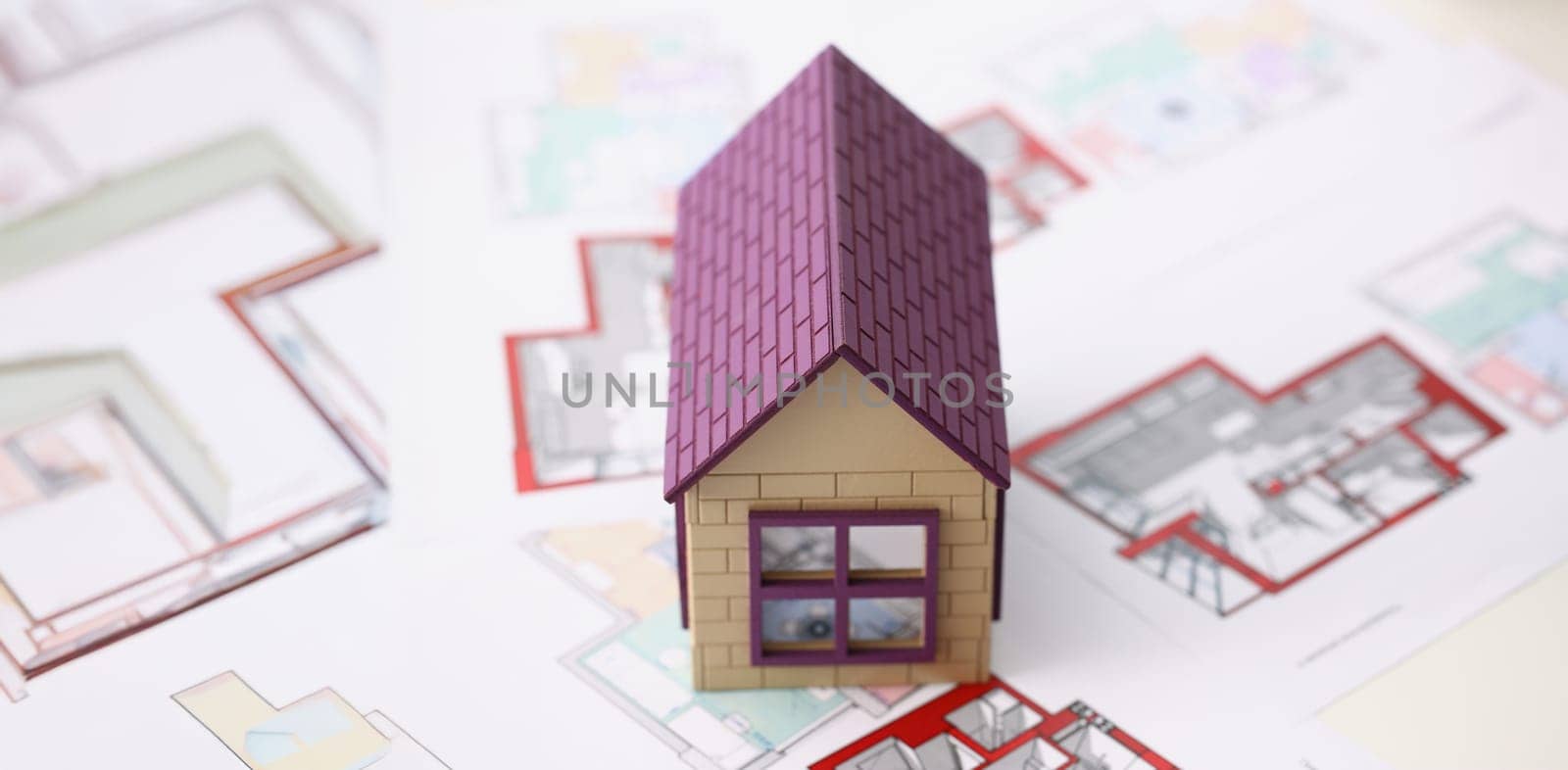 Close-up of house miniature with blueprint sample for real estate property development. Small model of future building. Real estate, architecture concept