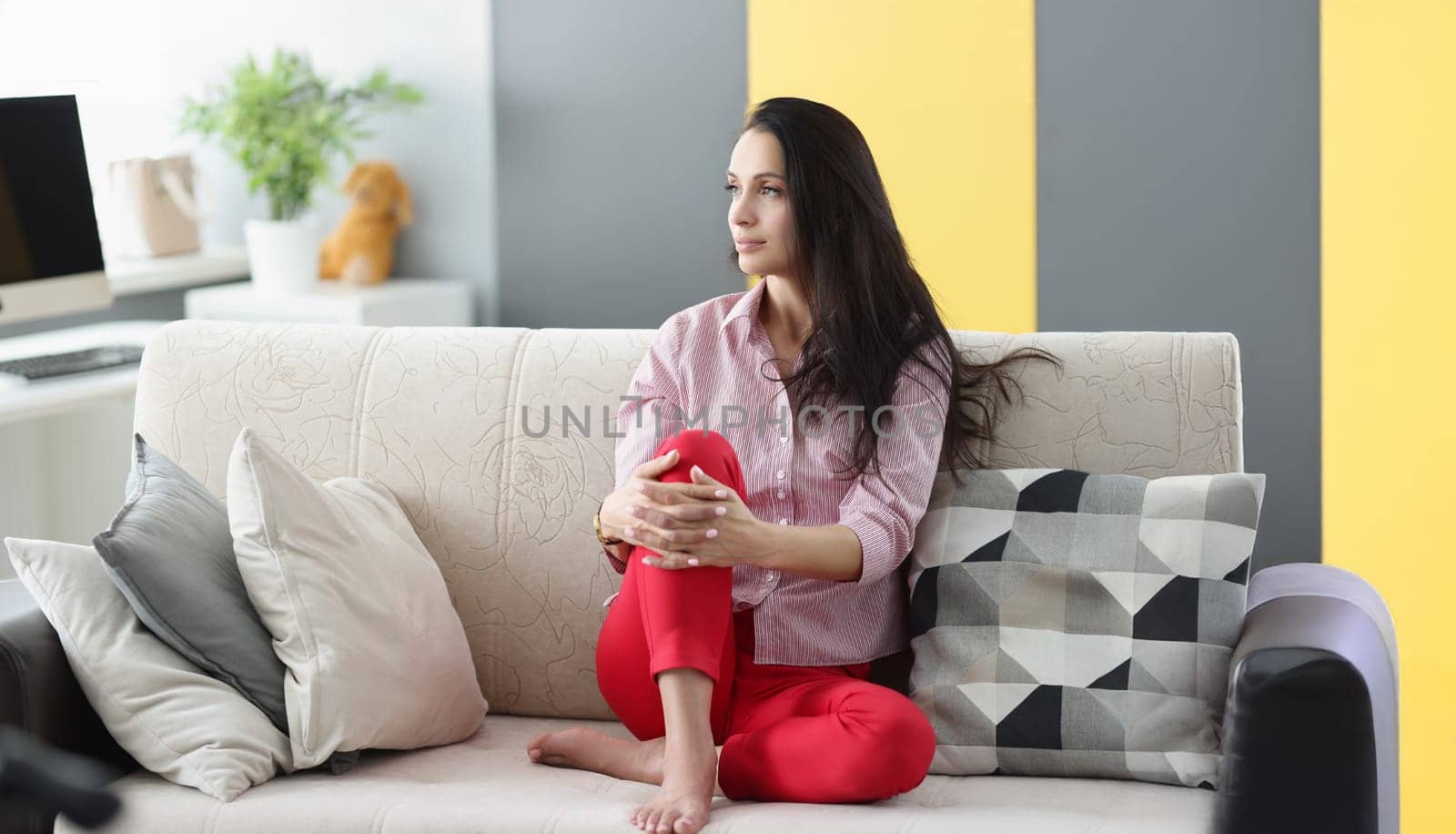 Portrait of brunette pensive young woman looking away sitting on couch at home. Female dreaming about holiday, make plans in mind. Interior, rest concept