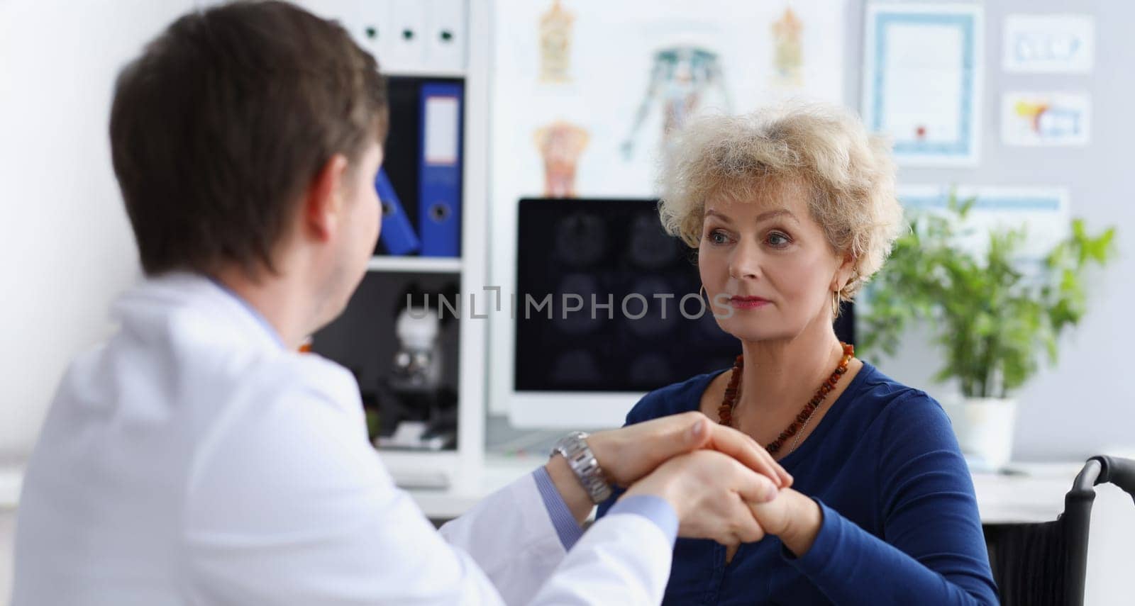 Portrait of professional doctor hold patients hand and calm down after appointment. Senior woman in doctors cabinet, checkup health. Medicine, help concept