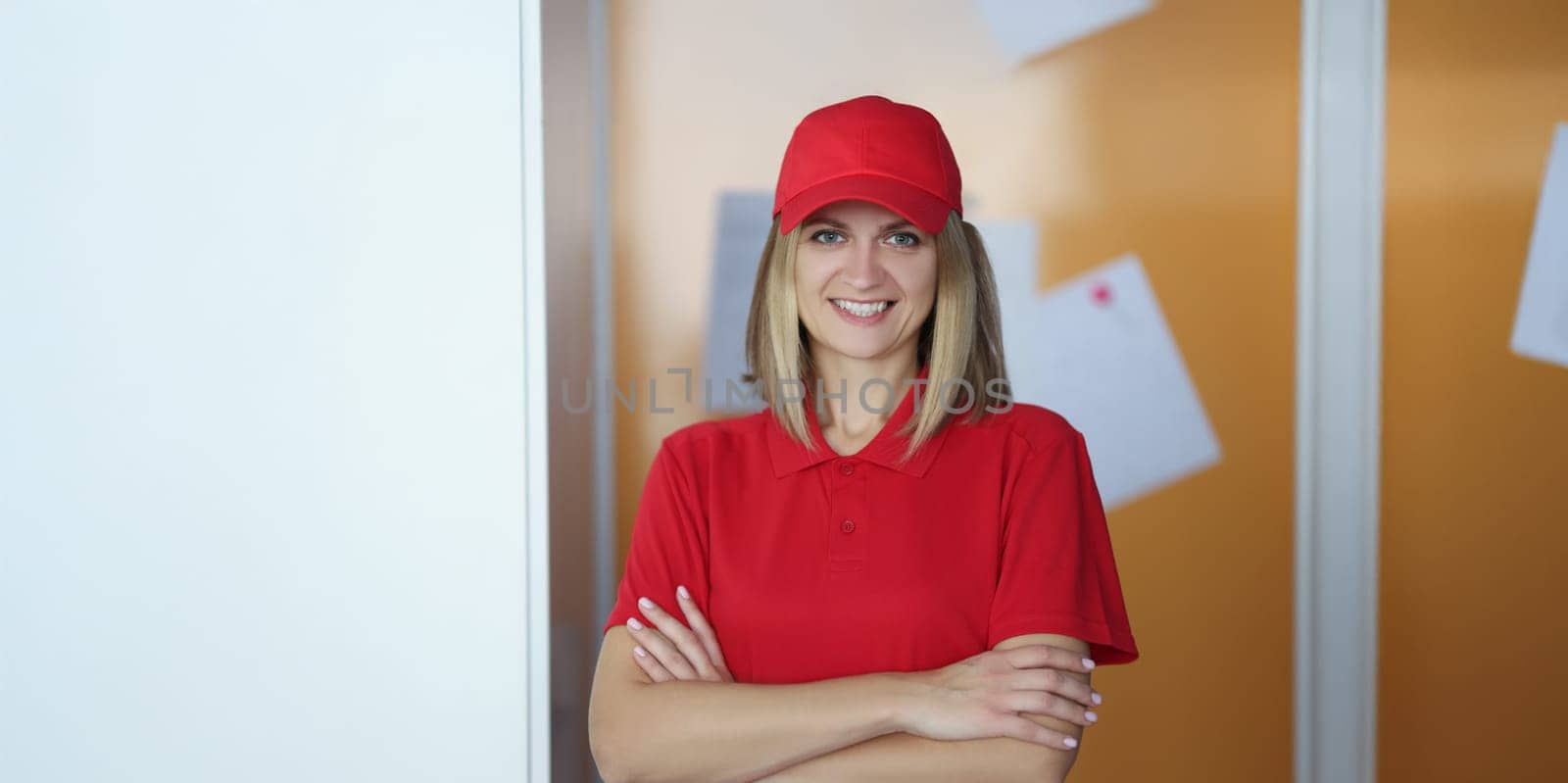 Portrait of happy blonde lady courier in red shirt and cap uniform. Positive mood, best worker of year. Delivery service, shipping, private courier concept
