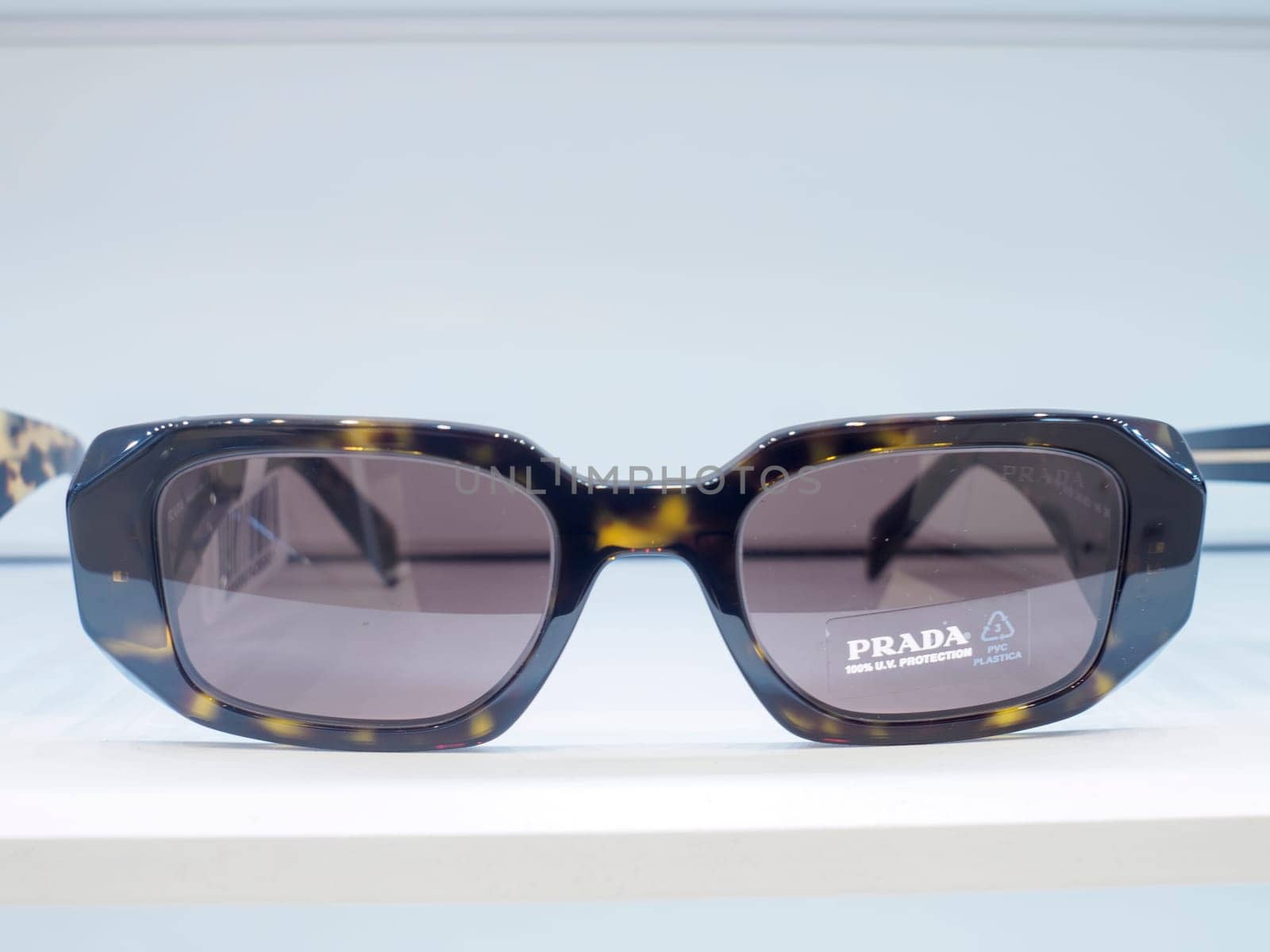 Stylish sunglasses with a tortoise pattern frame are displayed on a white surface, showcasing their modern design and sophisticated appeal