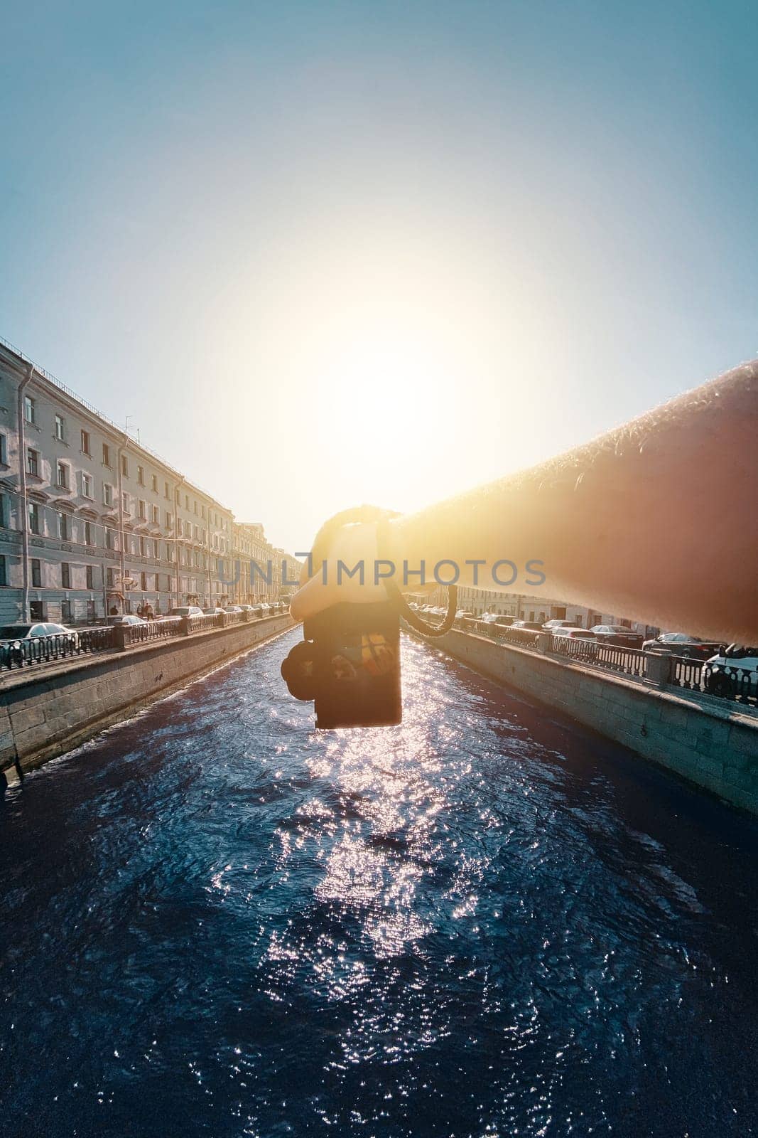 Holding a camera by the riverside amidst historic architecture, a male hand captures a photo from a first-person perspective. pov