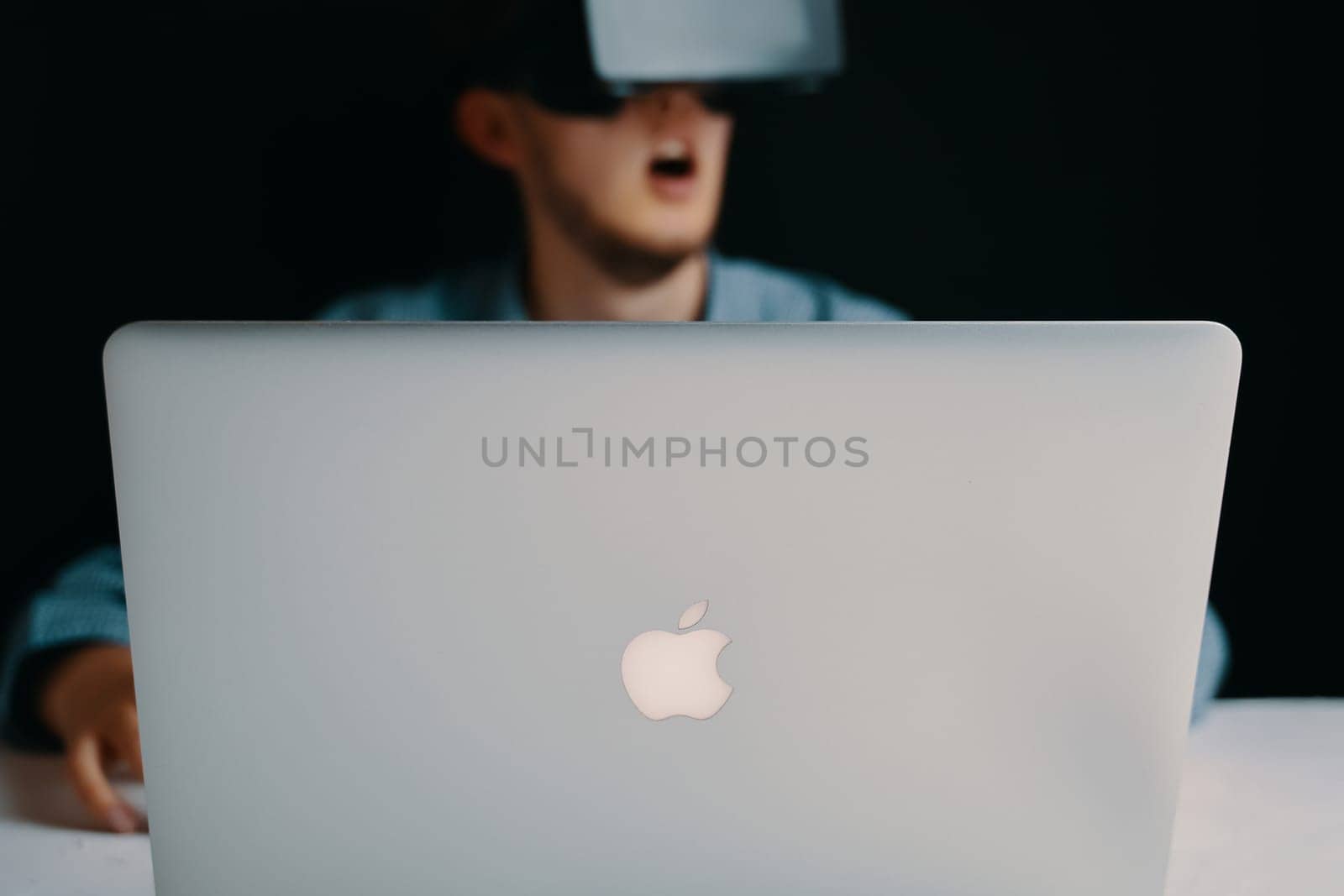 A man wearing a virtual reality headset is using a laptop computer for work. Bishkek, Kyrgyzstan - March 14, 2020