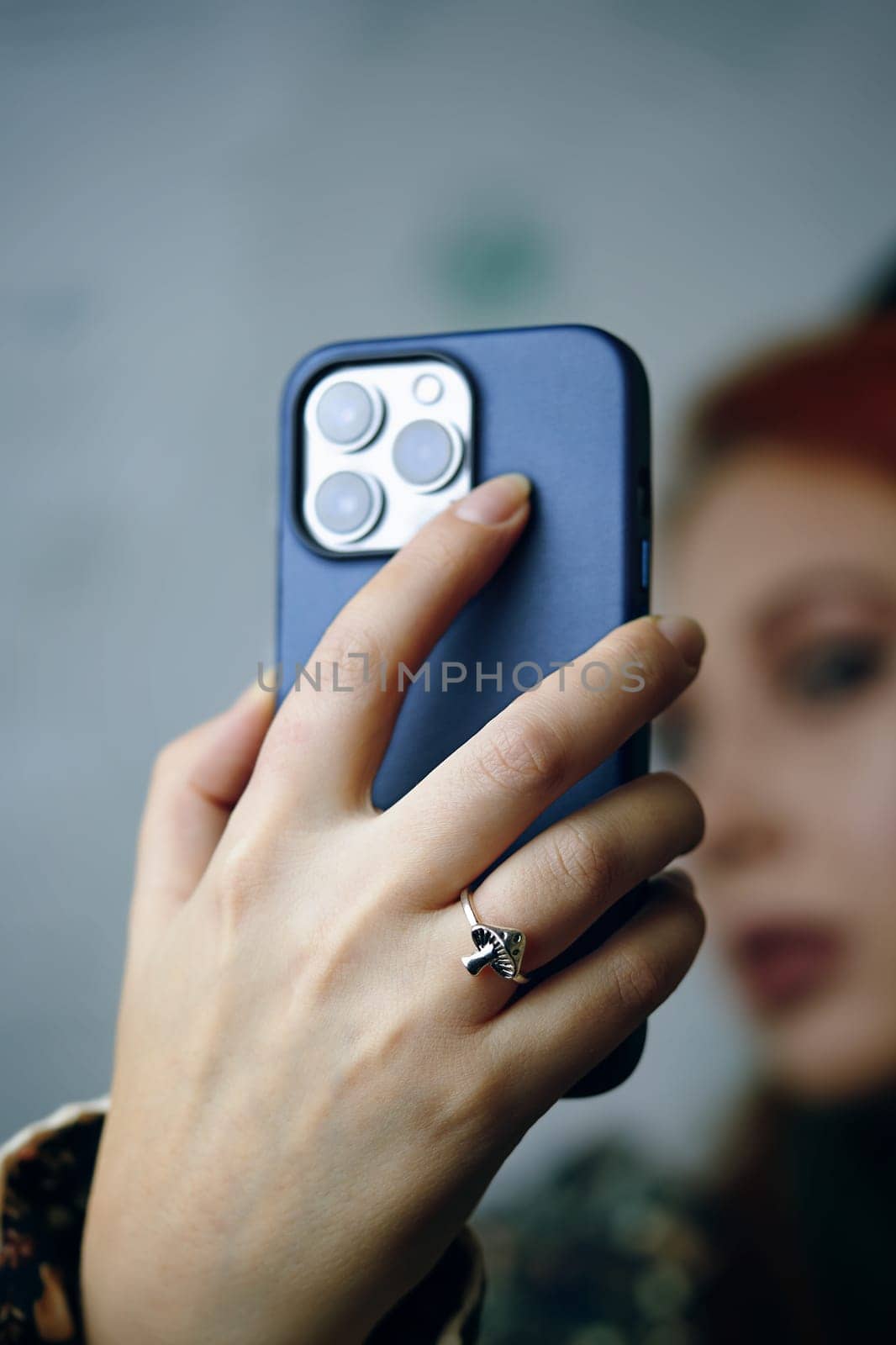 Close-up of female's hand holding smartphone in case. Attractive woman posing takes selfie on iPhone 13 pro. Gadget with triple-lens camera. Focus on foreground. Bishkek, Kyrgyzstan - January 24, 2022