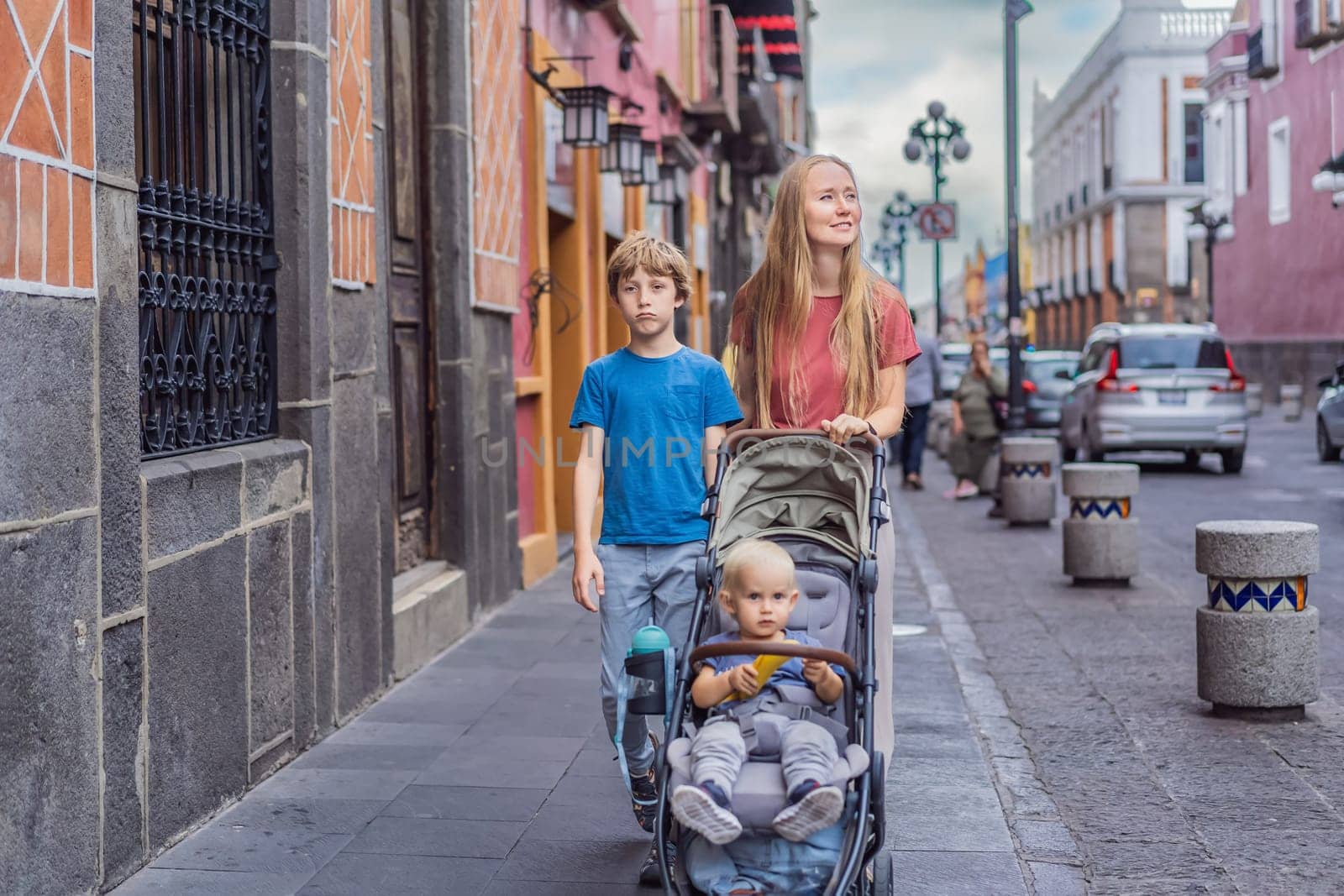 Mother tourist with her toddler and teenage sons walking through the colorful colonial streets of Puebla, Mexico. Travel, cultural exploration, and vibrant architecture concept.
