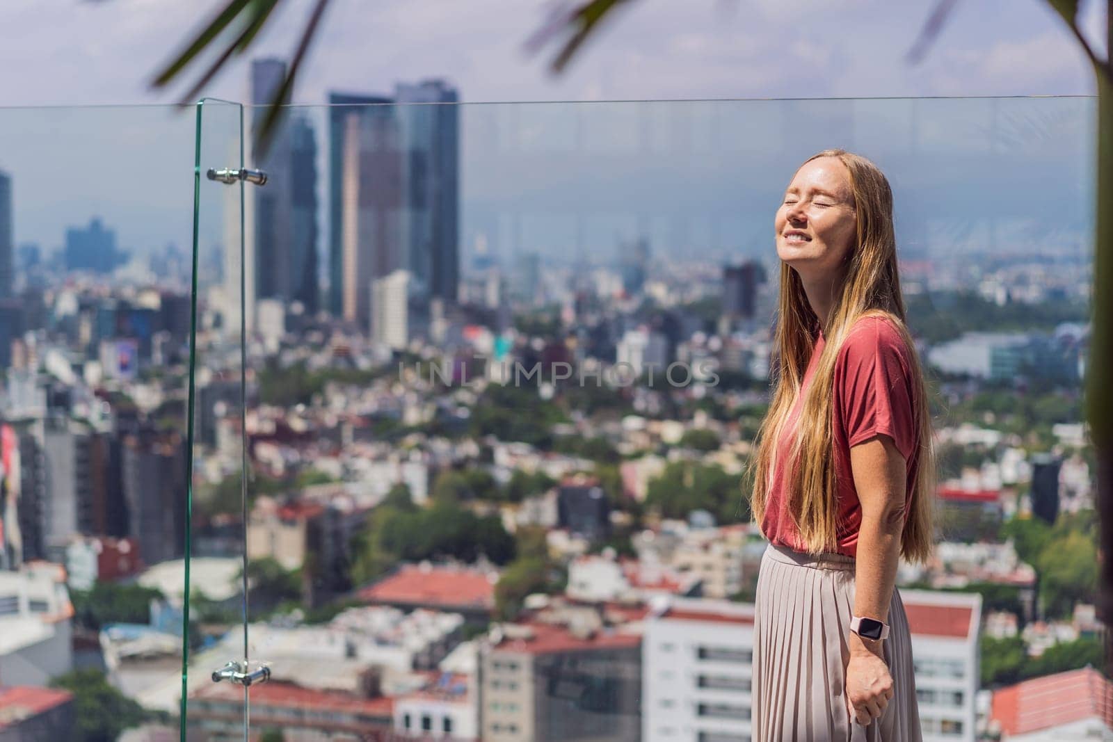 Female tourist or businesswoman standing on a skyscraper rooftop with a panoramic view of Mexico City. Travel or international business in Mexico concept.