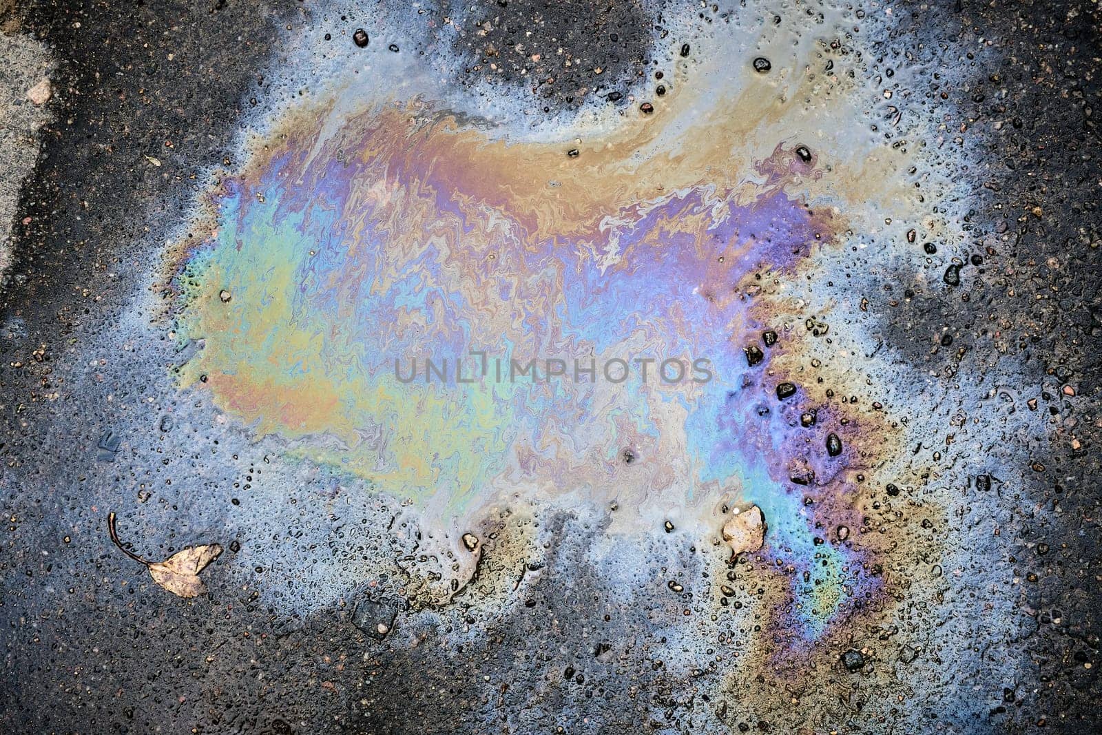 A car leaking oil or gasoline onto a wet asphalt road on a wet fall day.
