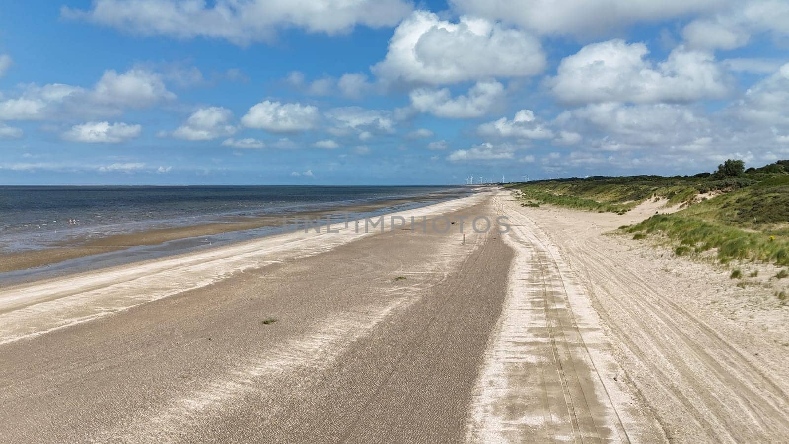 a photo taken of the North Sea beach at Rockanje in the Netherlands in the summer with the windmills in the background