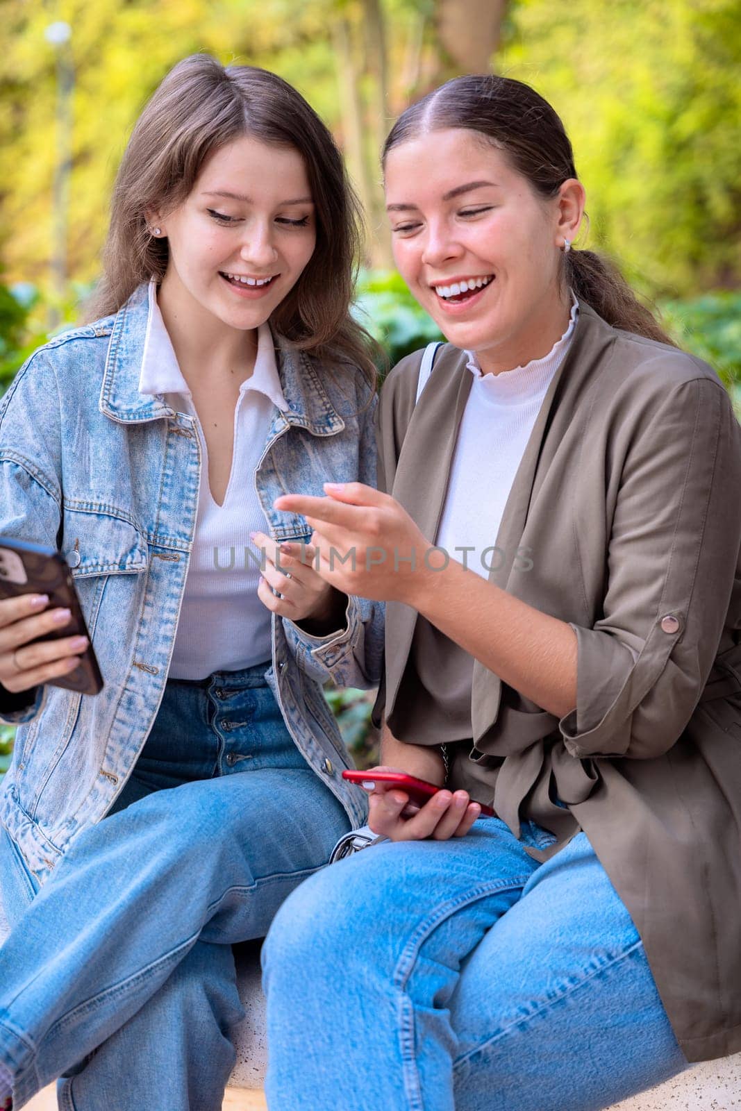 two young friends pointing at something while browsing social media on the phone.