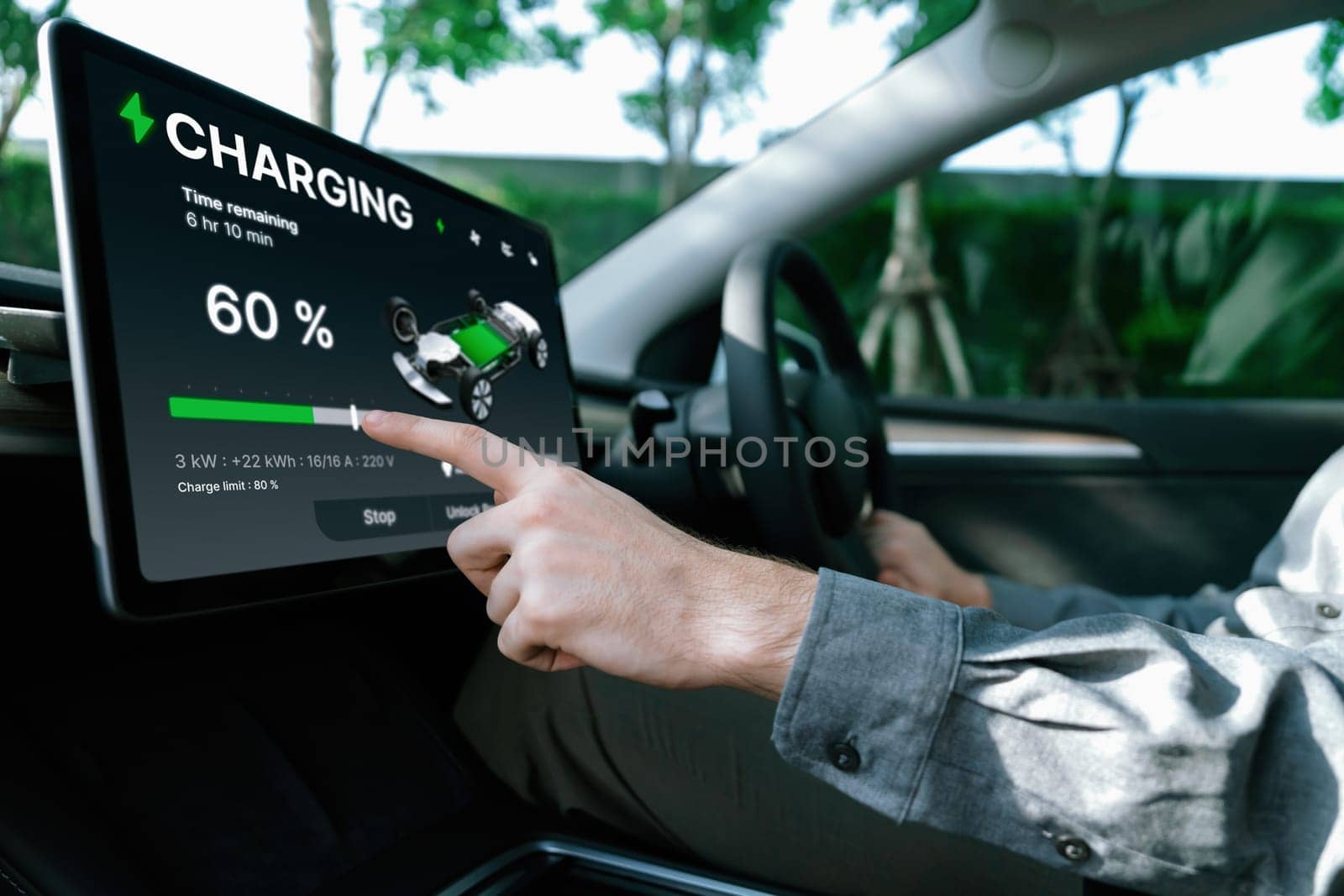 Electric car driver checks battery charging status app screen in car innards by biancoblue