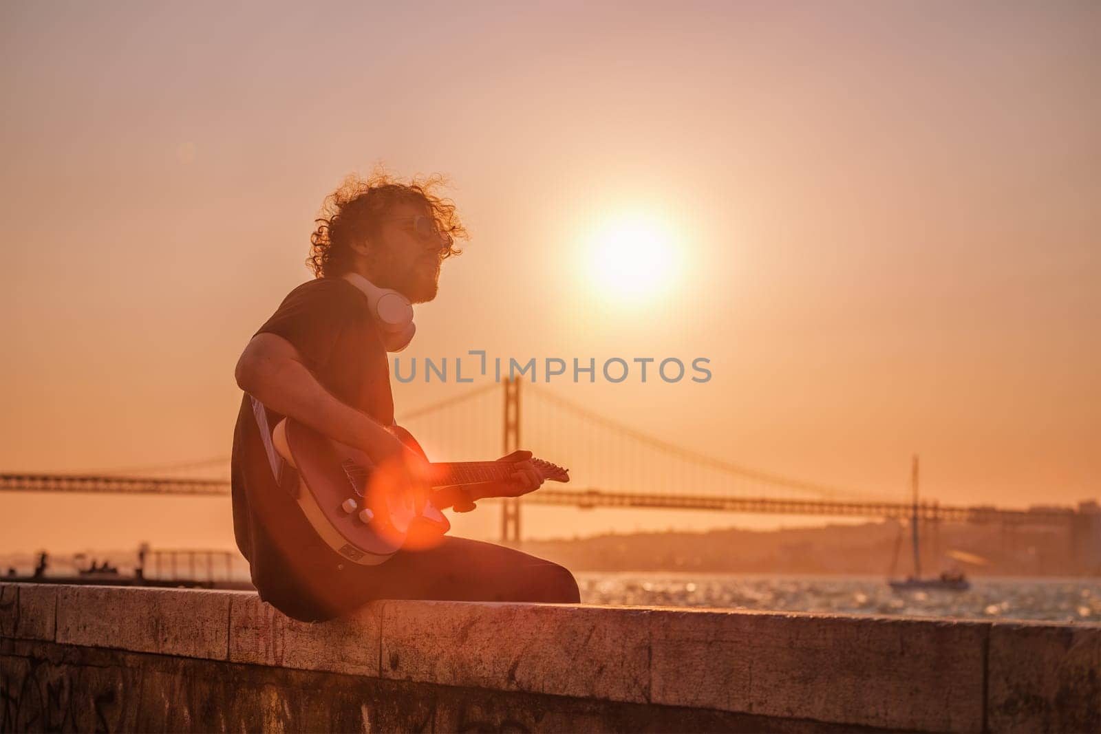 Hipster street musician in black playing electric guitar in the street on sunset