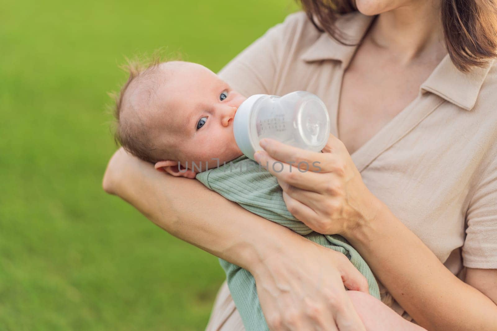 Mother giving to drink water baby from bottle, closeup by galitskaya