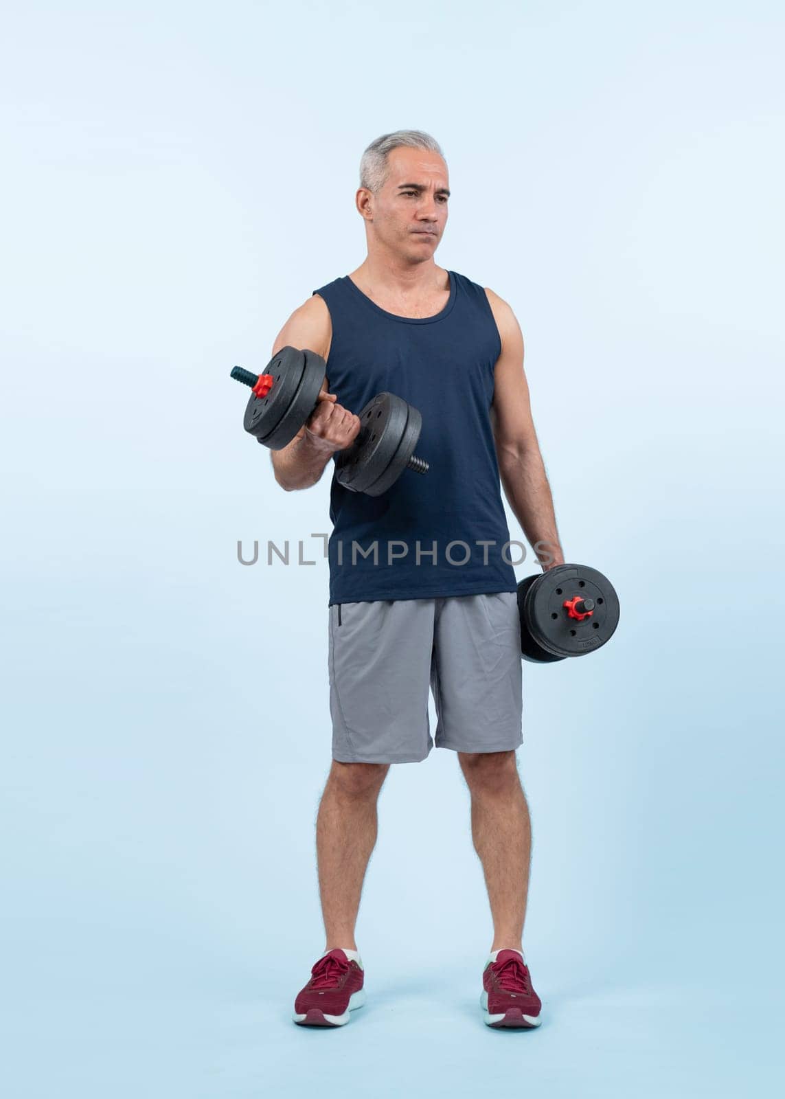 Full body length shot active and sporty senior man lifting dumbbell. Clout by biancoblue